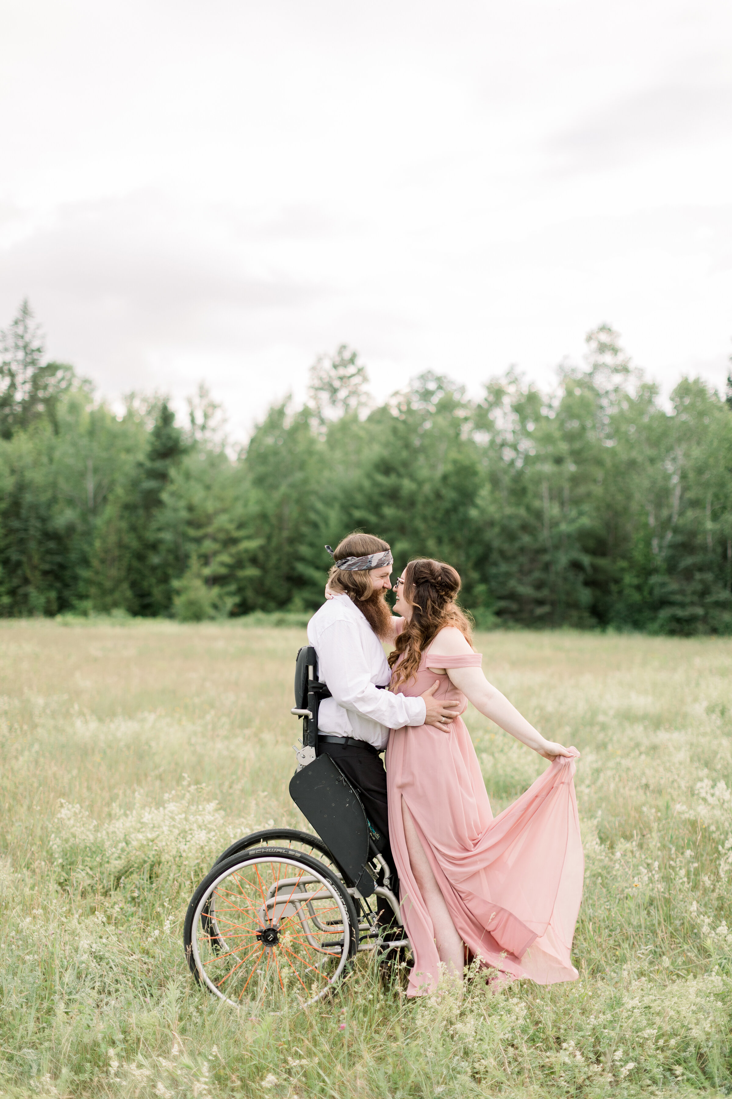  Groom stands in his standup chair and holds his beautiful bride to be in a stunning rustic styled engagement session in Smith Falls. Ontario Canada flowing pink dress inspiration engagement session goals standup chair pose inspiration ideas and goal