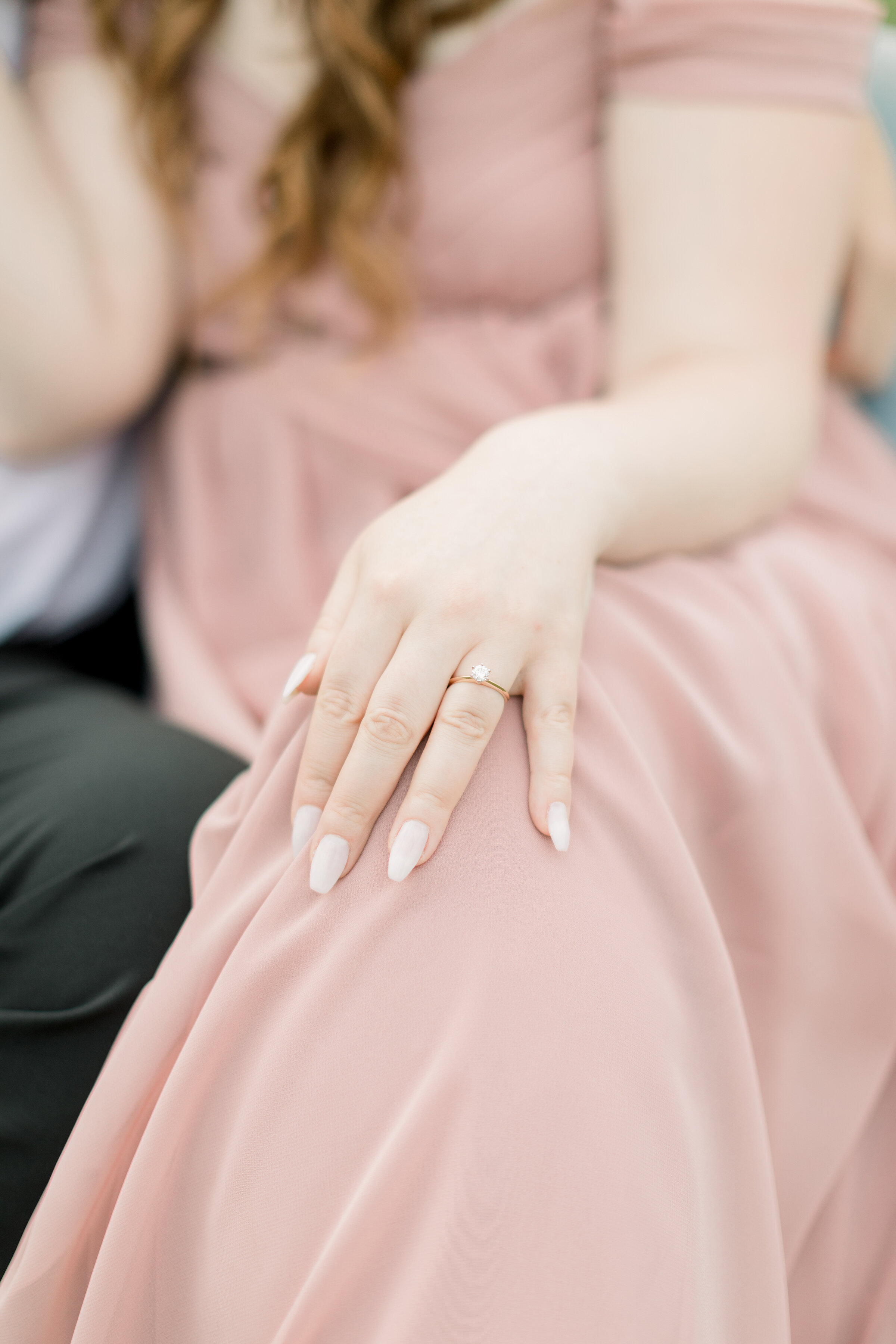  A stunning look at the engagement ring as she gently lays her hand on her dusty rose pink dress in a beautiful engagement session by professional engagement photographer Chelsea Mason Photography. Showing off the ring pose inspiration nail goals eng