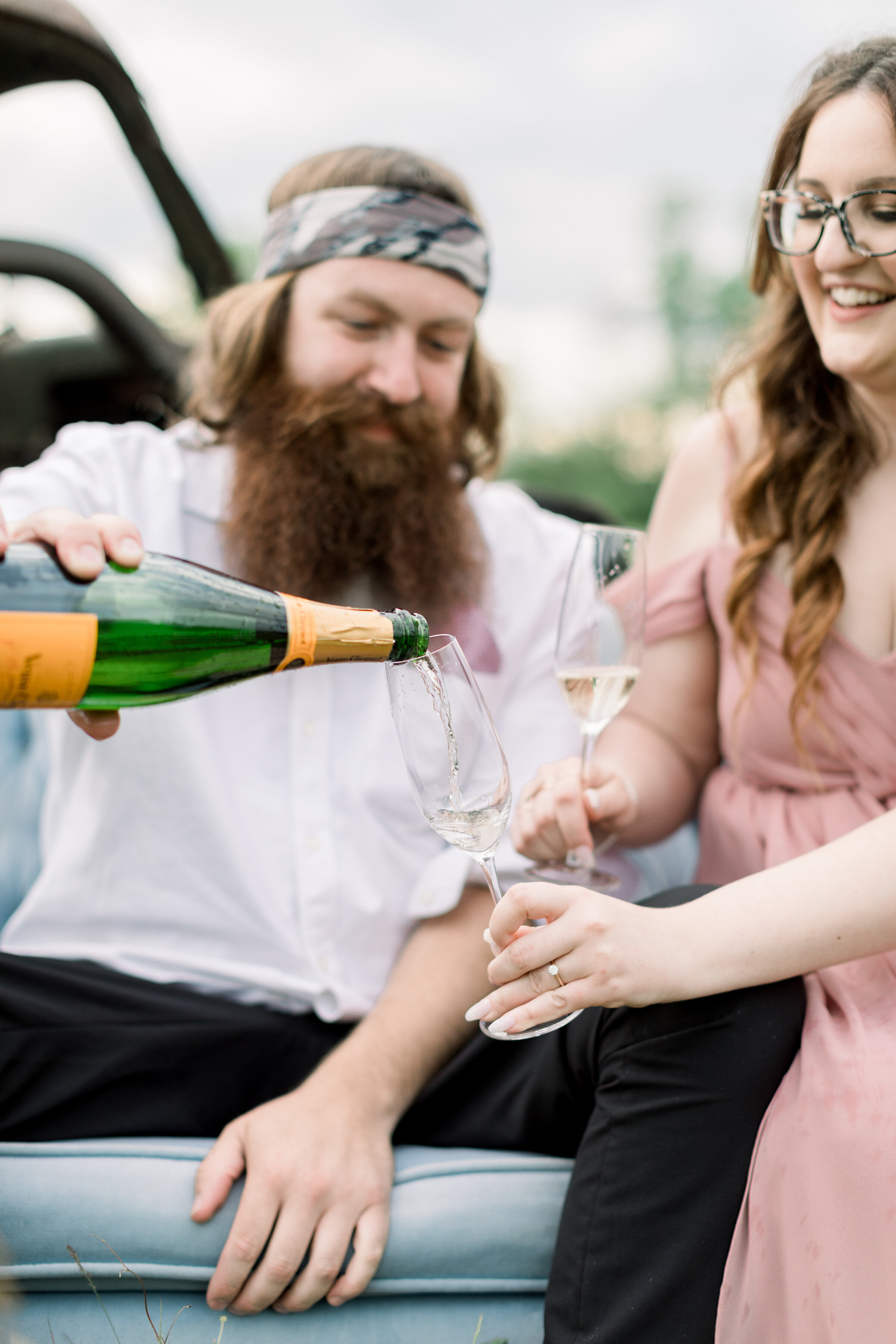  The groom pours the Champagne for his soon to be bride in a beautiful outdoor engagement photo shoot by professional engagement photographer Chelsea Mason Photography. Engagement session inspiration ideas and goals sitting couple pose inspiration po