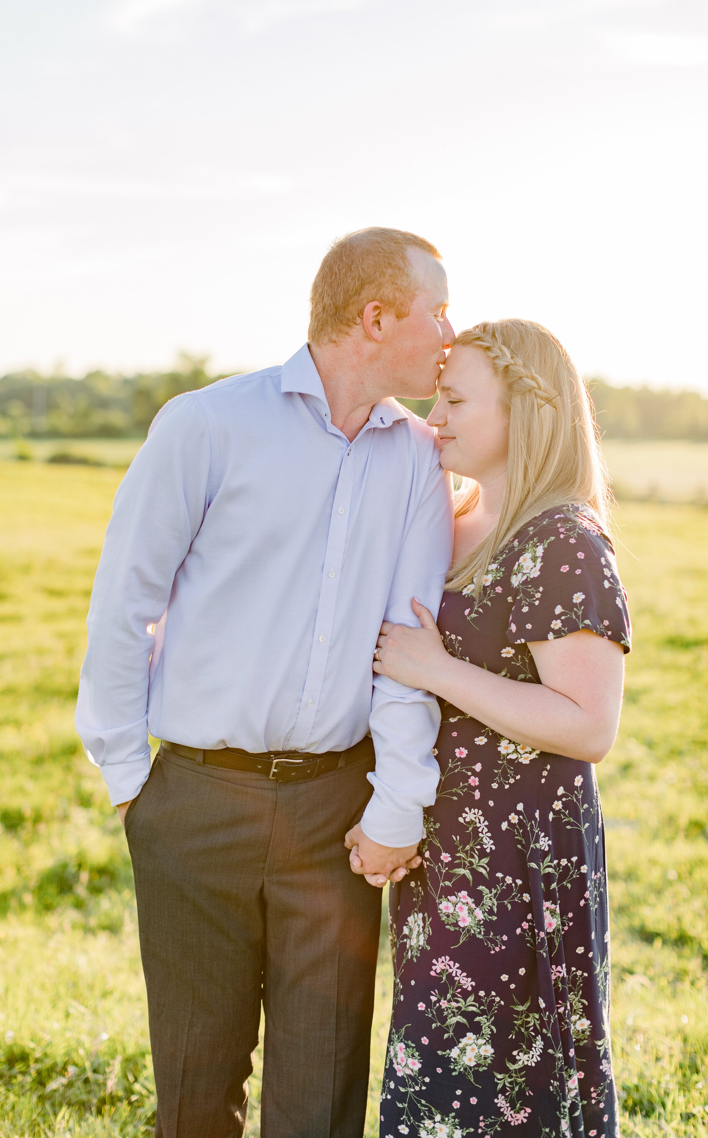  Groom kisses his glowing bride to be on the forehead in a bright and airy country styled engagement session in Perth, Ottawa. Location inspiration for engagement sessions couple goals couple pose inspiration outdoor photo shoot inspiration ideas and