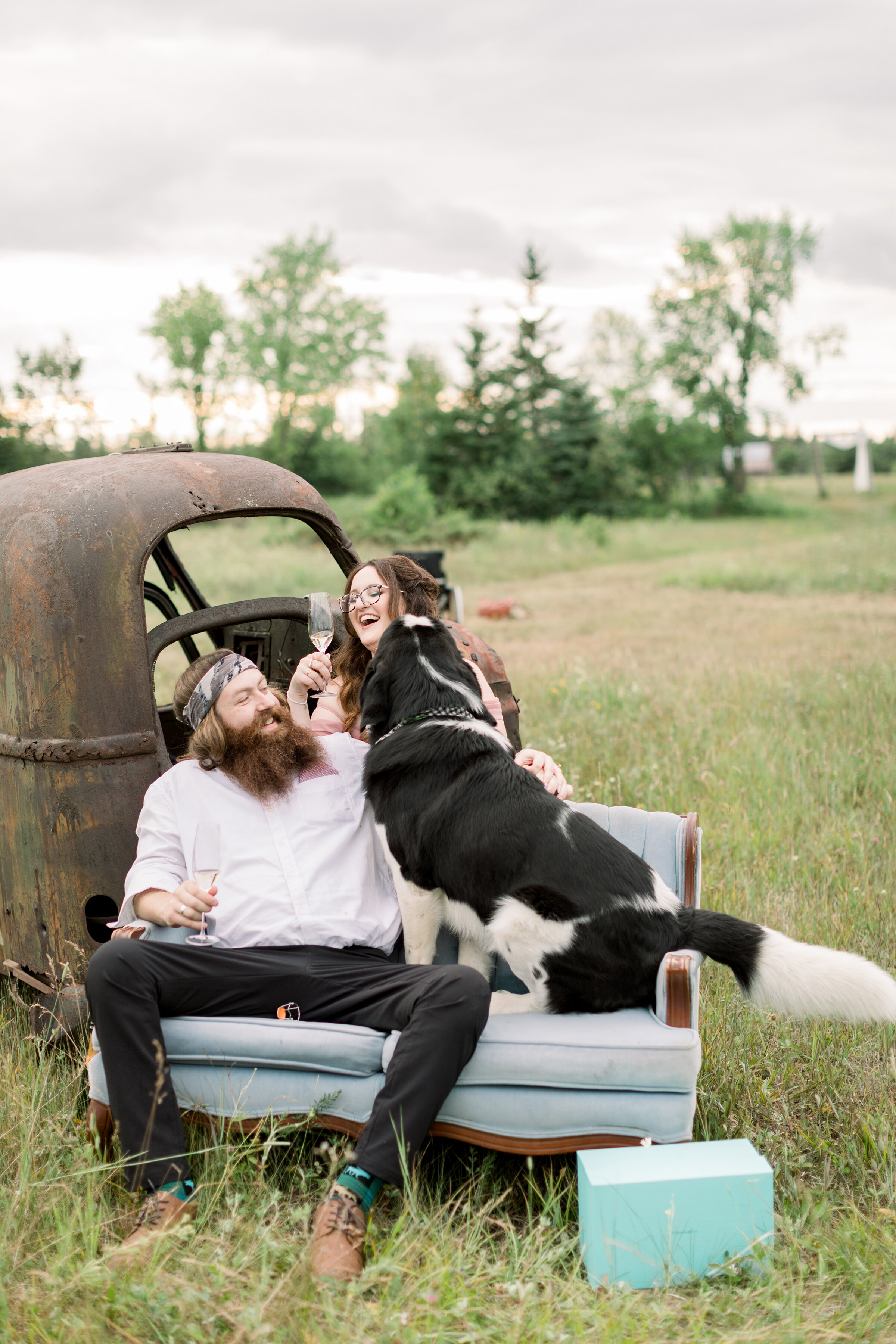  A couple laugh at their silly pup as they drink their Champaign in a rustic and unique out door engagement session by professional engagement photographer Chelsea Mason Photography. Engagement goals engagement prop inspiration ideas and goals for ru