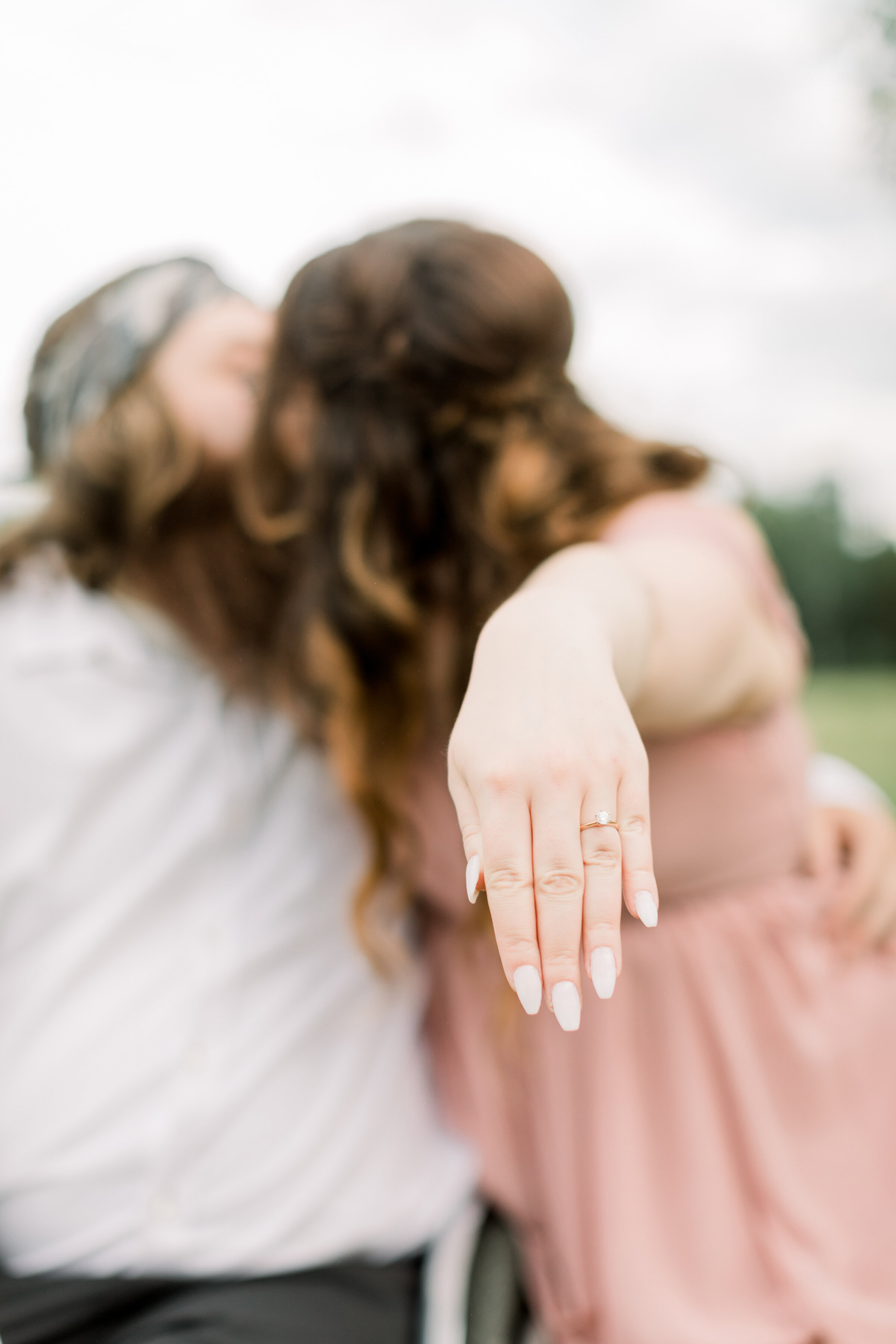  A bride shows off her stunning and simple ring while kissing her man in a beautiful outdoor engagement photo shoot by Chelsea Mason Photography. Couple goals showing off the ring pose inspiration ideas and goals client attire inspiration ideas and g