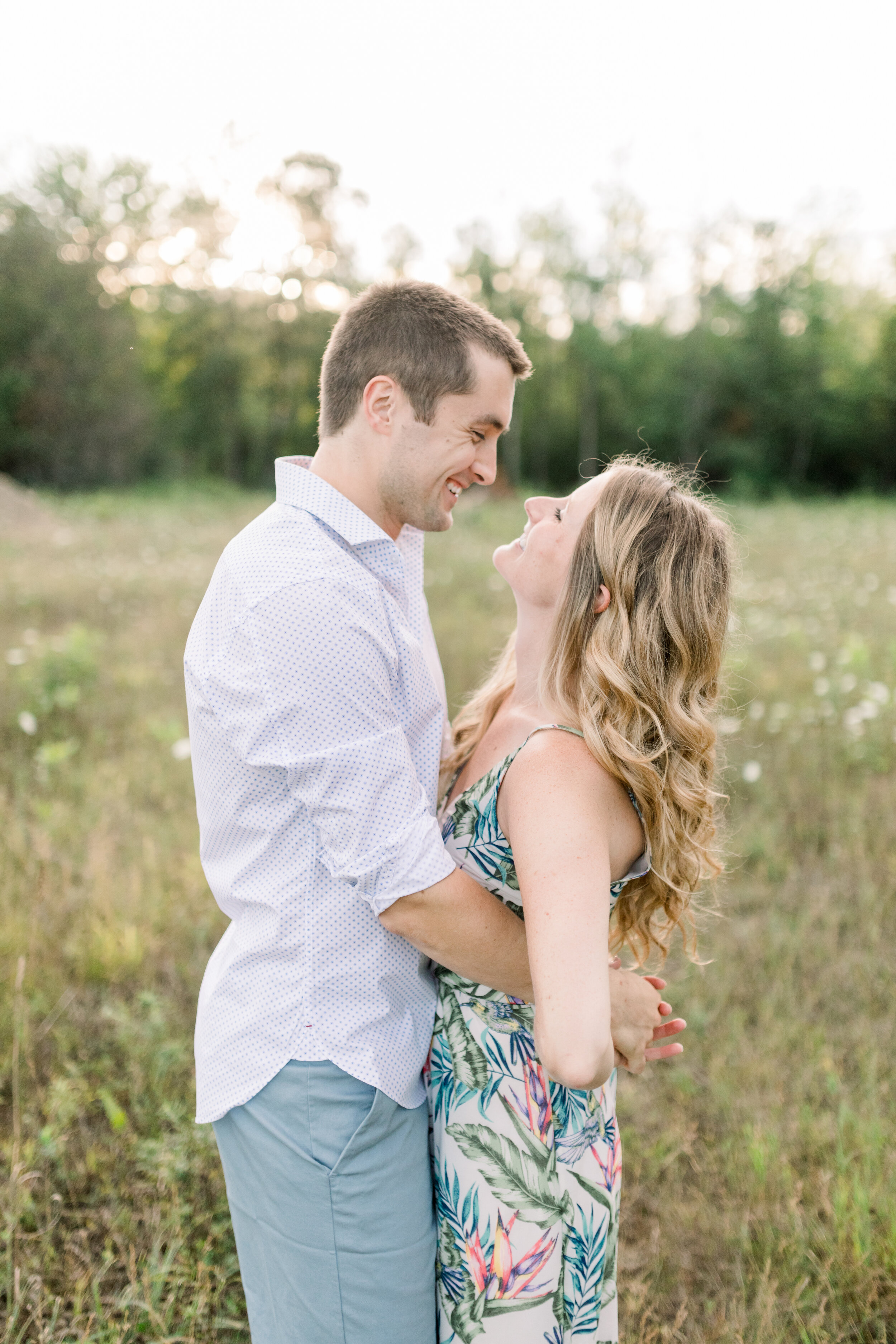  With his arms linked behind her back, Ottawa, Canada’s Chelsea Mason Photography captures an elated groom beaming down at his bride during this wildflower engagement session. hugging engaged couple, wildflower field ottawa canada, rolled up long sle