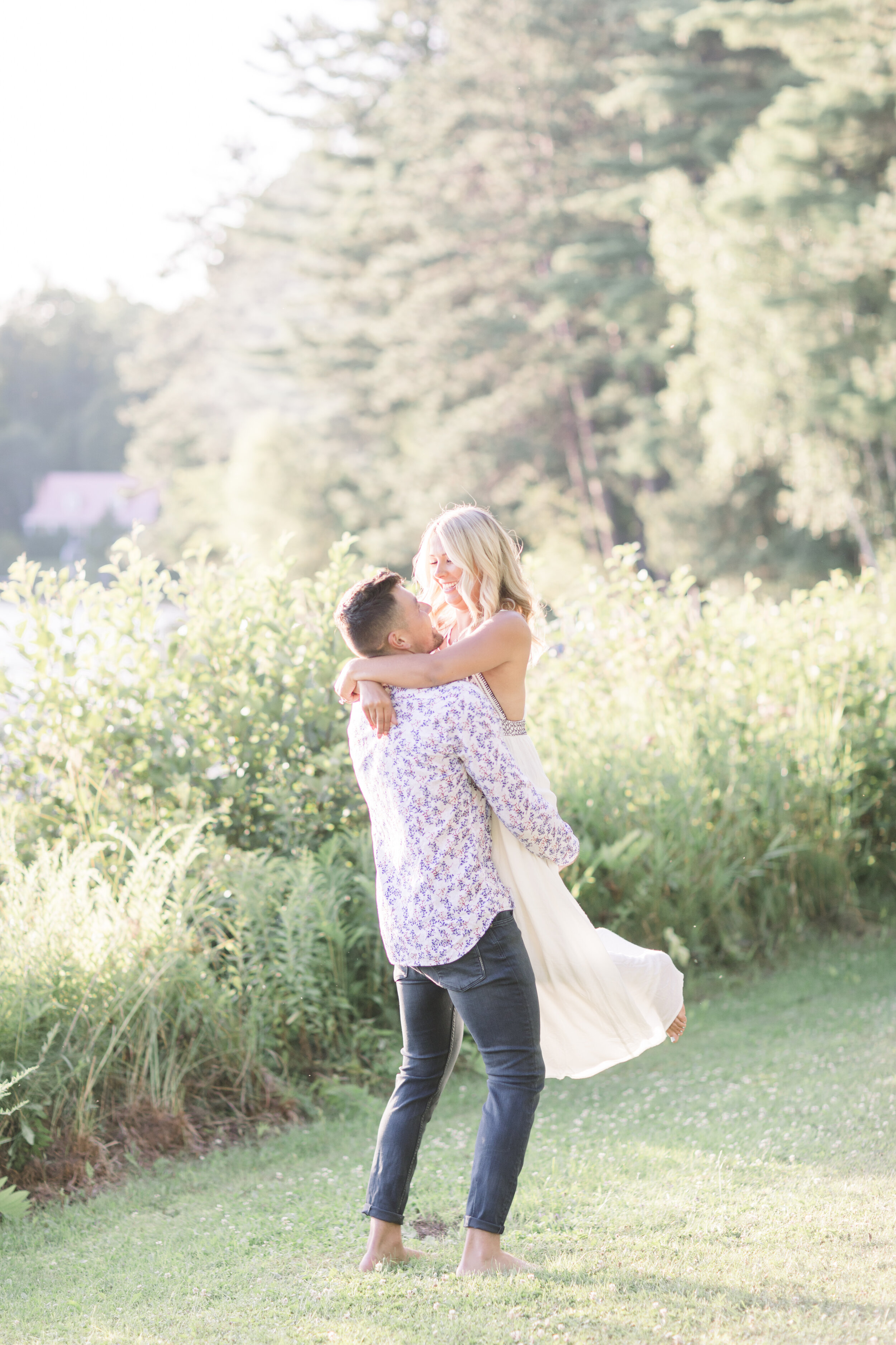  Barefoot couple in quebec dancing playfully in the grass during their sunset cottage engagement session. Boho engagement session white dress for engagement session playful engagement session posing inspo engagement photographer in quebec best poses 