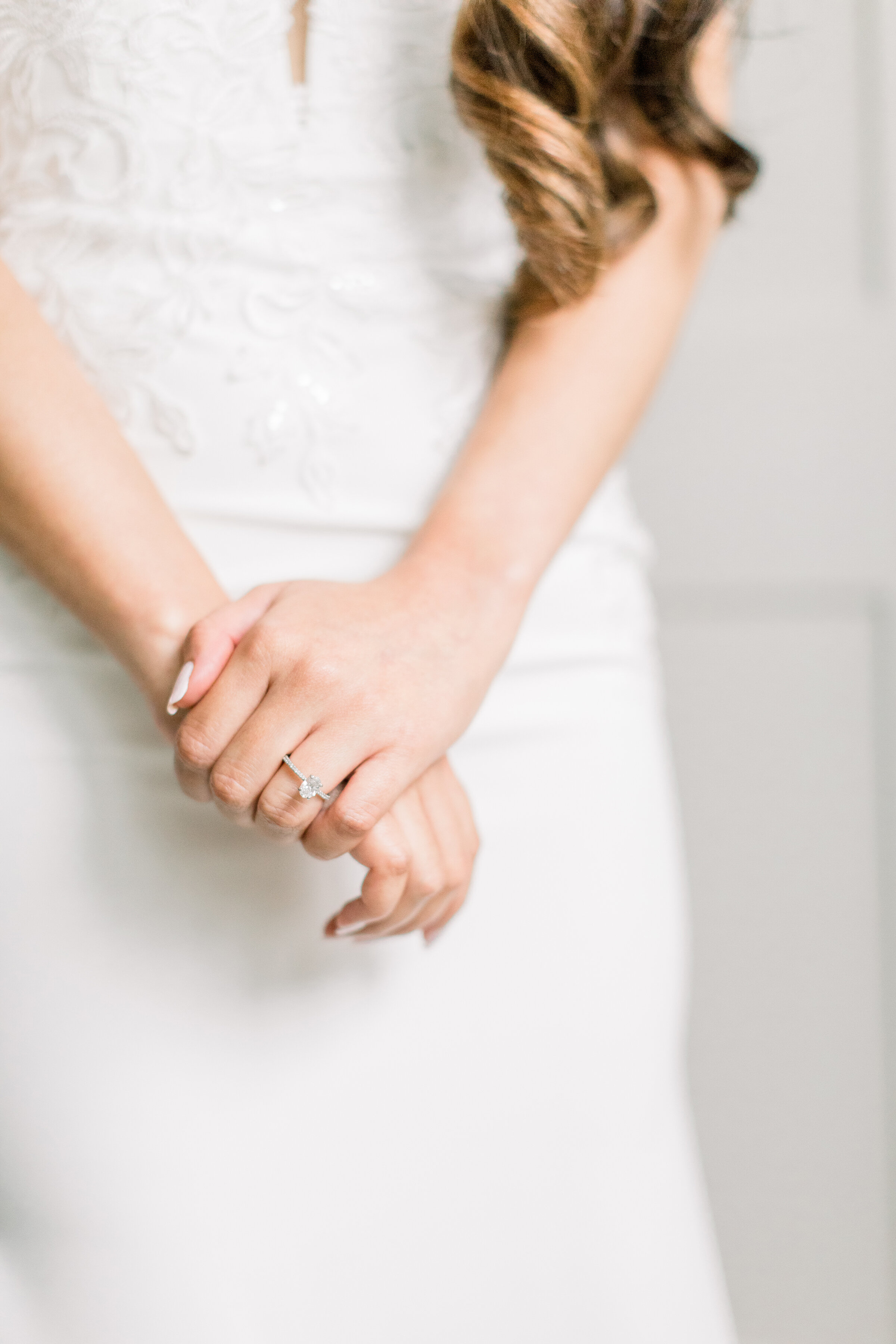  A beautiful bride holds her hands as she shows her simple and stunning ring as her ringleted hair falls on her arm in a stunning close up wedding session by Chelsea Mason Photography in Stonefields Estates, Ottawa. Wedding pose inspiration just the 