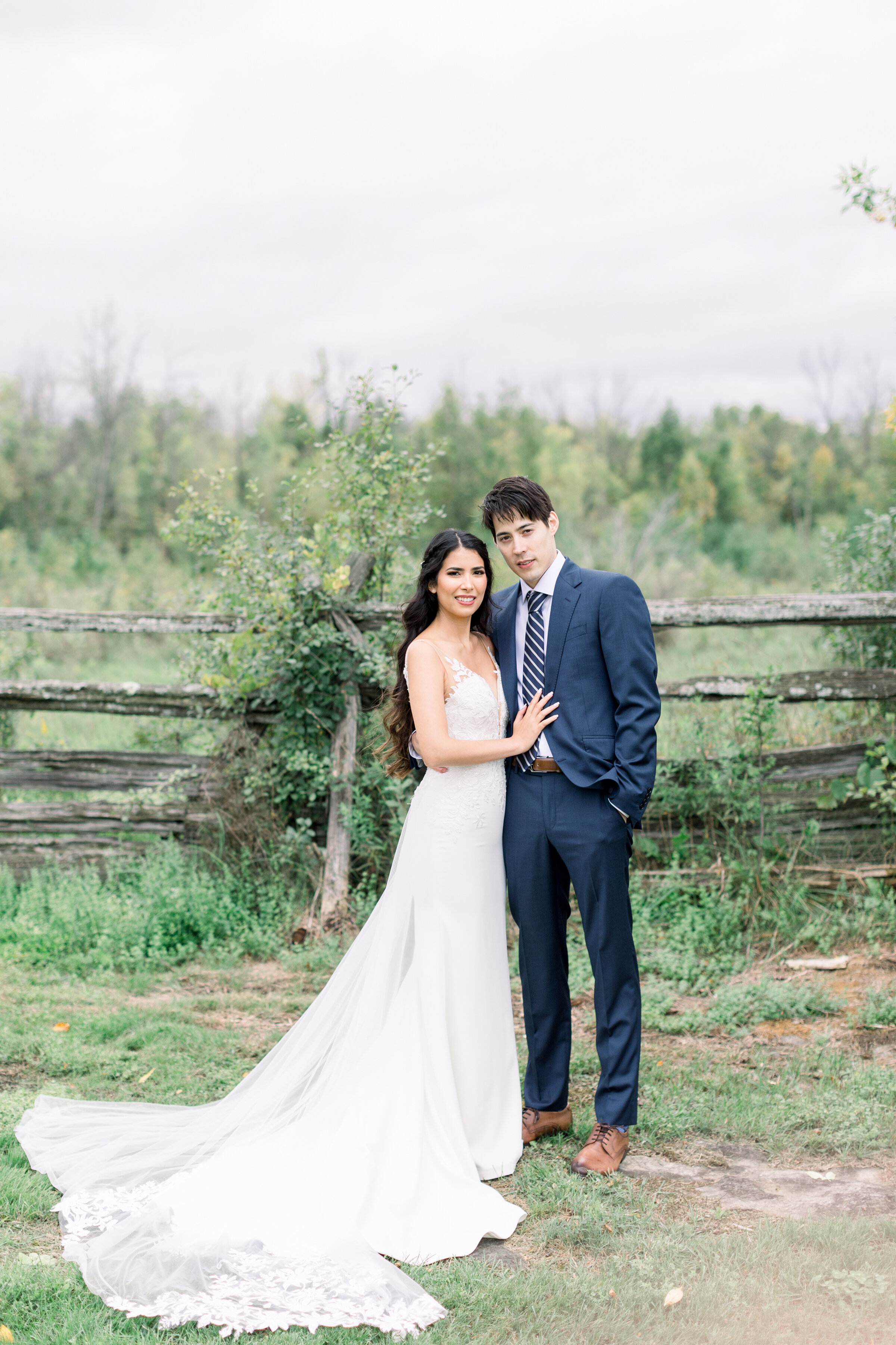  A stunning soon to be husband and wife stand together in front of a rustic fence on the Stonefields Estates, Carleton Place in Ottawa by professional wedding photographer Chelsea Mason Photography. Couple pose inspiration for wedding wedding goals w