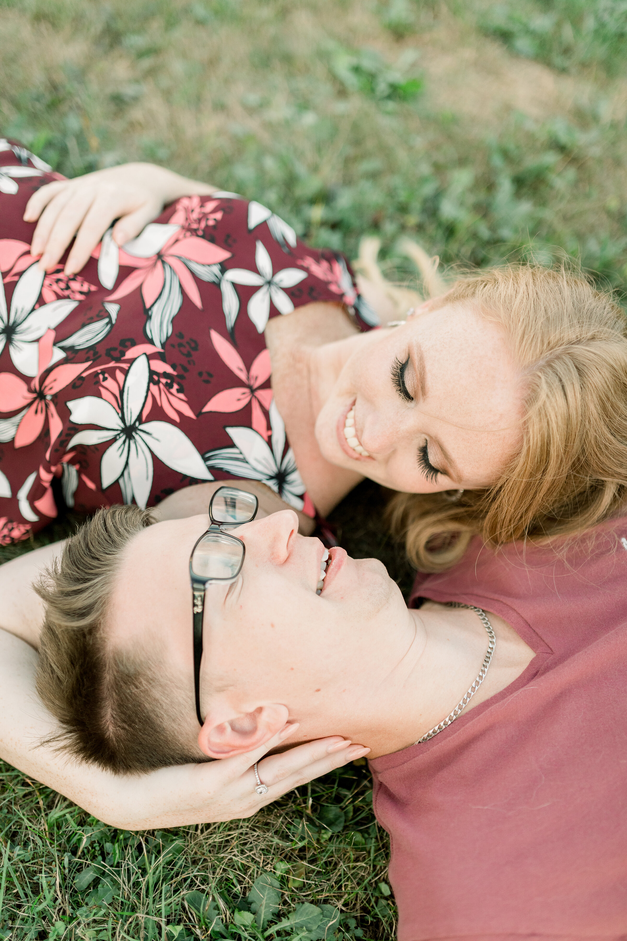  A happy couple cradle each others heads as they look into each others eyes in a engagement session by Chelsea Mason Photography at Dominion Arboretum in Ottawa. Professional Ottawa engagement photographer couple goals couple pose inspiration laying 