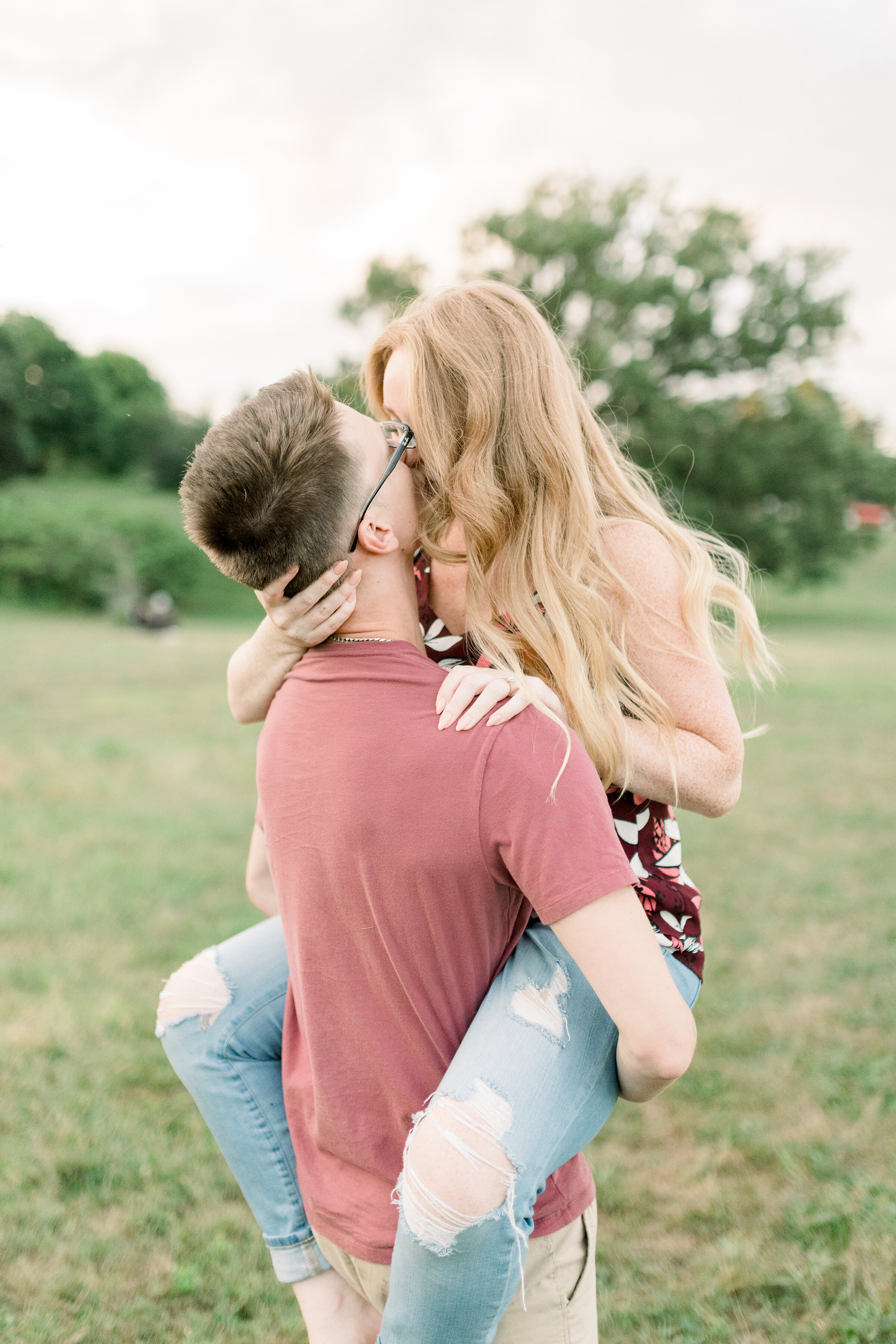  A loving newly engaged couple kiss as she wraps her legs around him in a stunning engagement session at Dominion Arboretum in Ottawa. Engagement location inspiration in Ottawa couple goals couple pose inspiration couple pose goals client attire insp