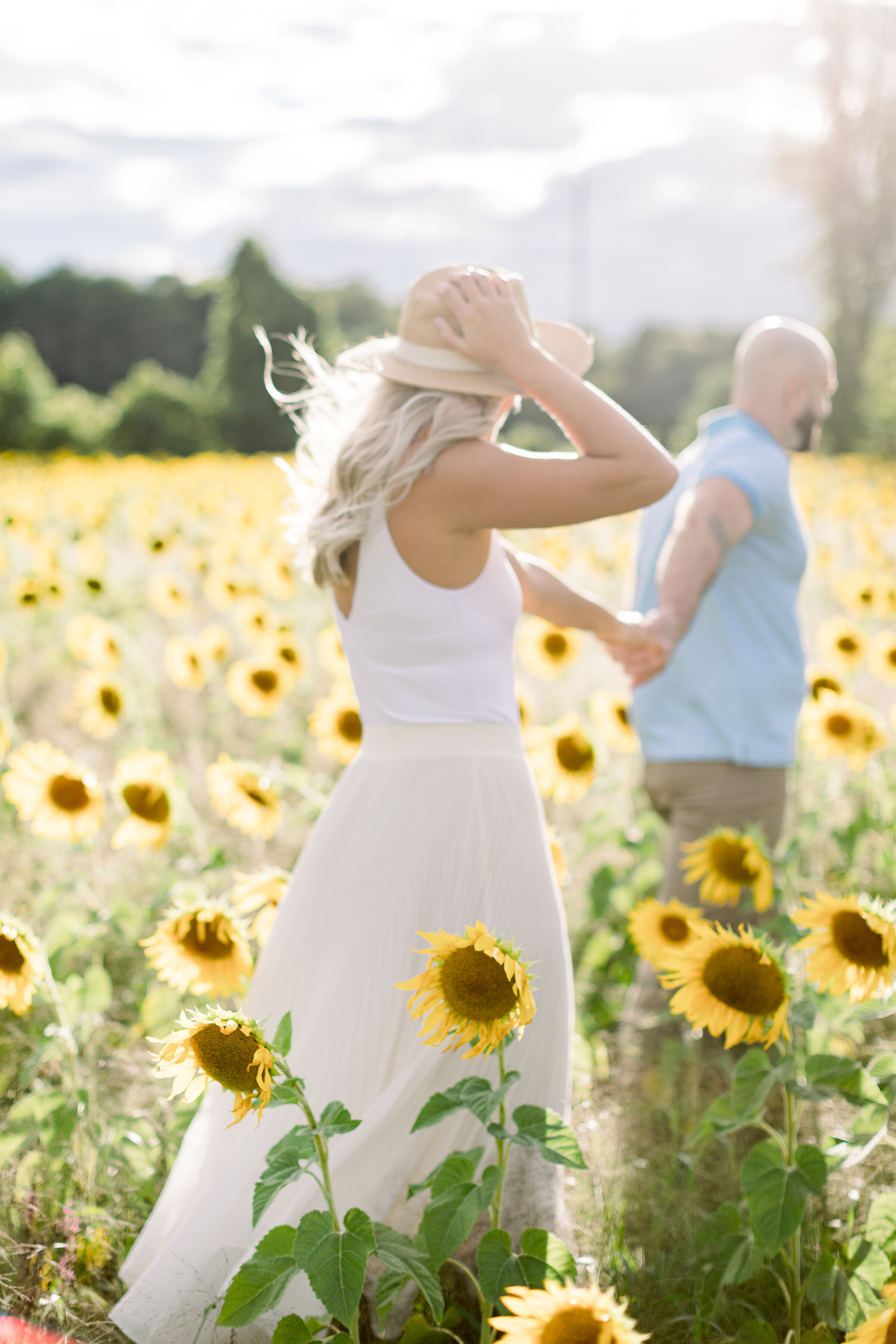  A handsome groom leads his glowing fiancé through the sunflowers in a bright and airy engagement session in Ottawa, Ontario by professional engagement photographer Chelsea Mason Photography. Engagement session goals ideas and inspiration couple goal