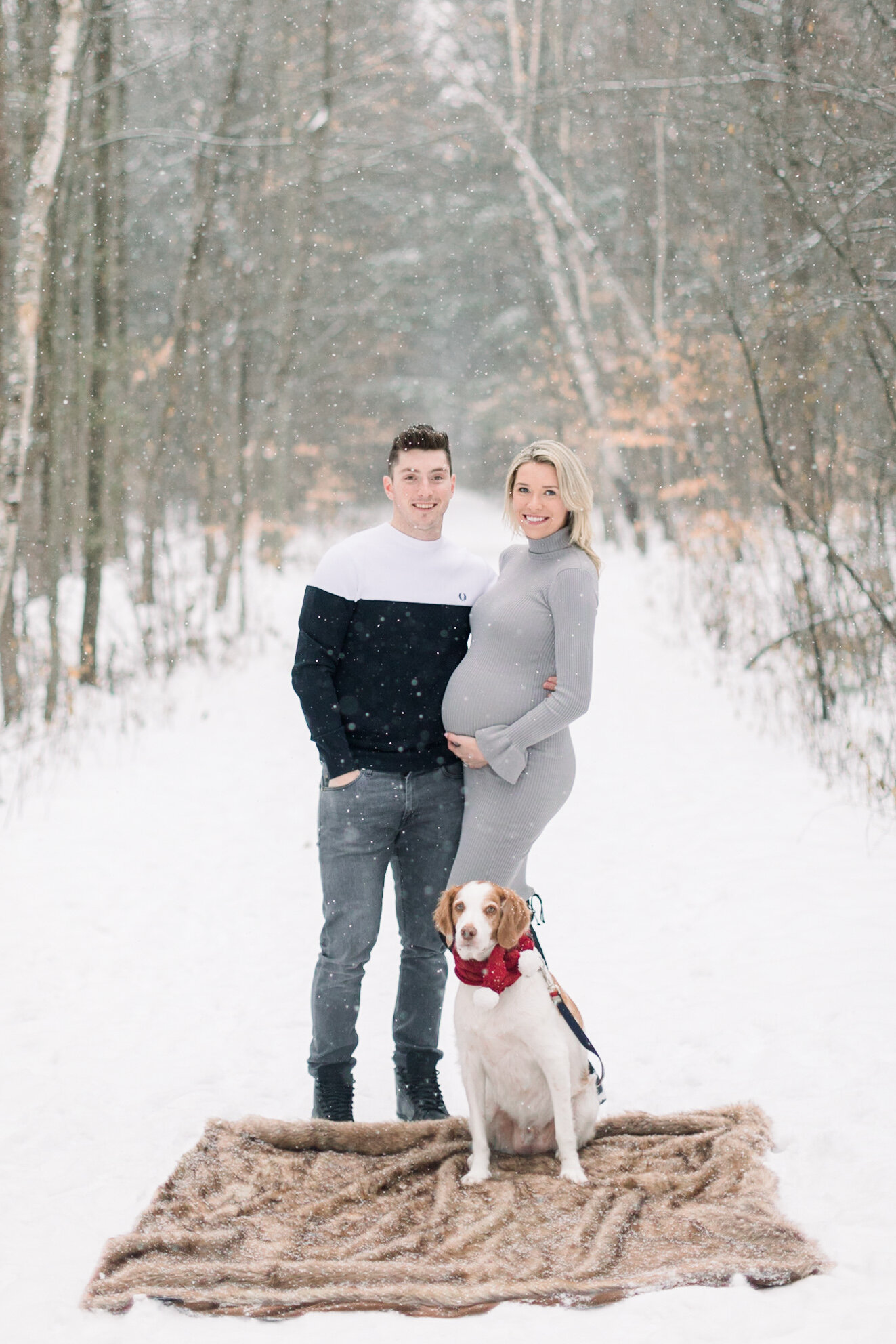  A glowing couple stand with their cute dog on Pinhey’s Trails in Ottawa in a beautiful winter maternity session by Chelsea Mason Photography.  Maternity couple pose inspiration ideas and goals couple goals winter client attire for men and women outd
