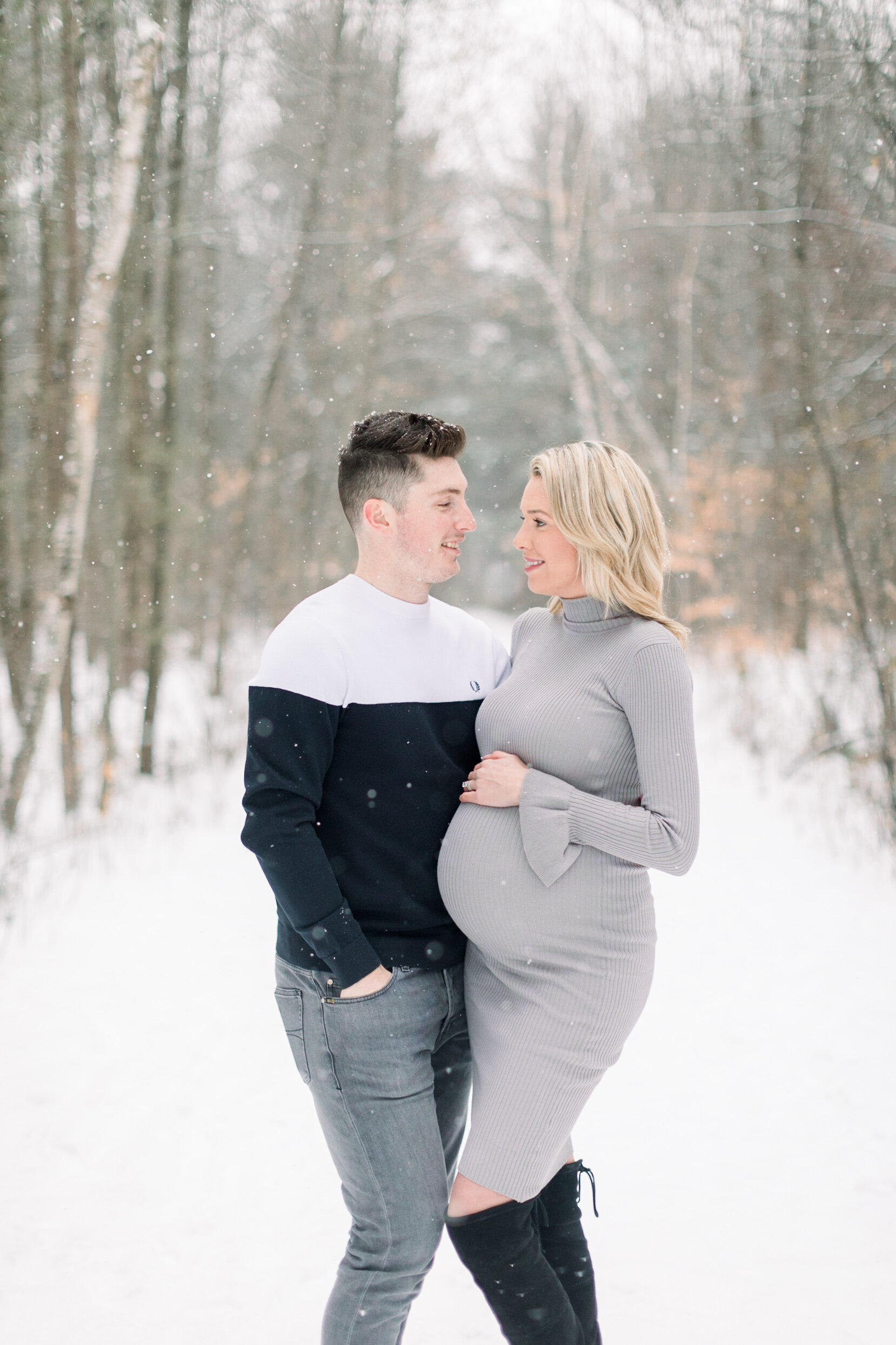  A loving couple look into each others eyes as she holds her pregnant belly in a beautiful Pinhey’s Trails maternity photo shoot in Ottawa. Professional maternity photographer Chelsea Mason Photography winter photo shoot maternity sweater dress inspi