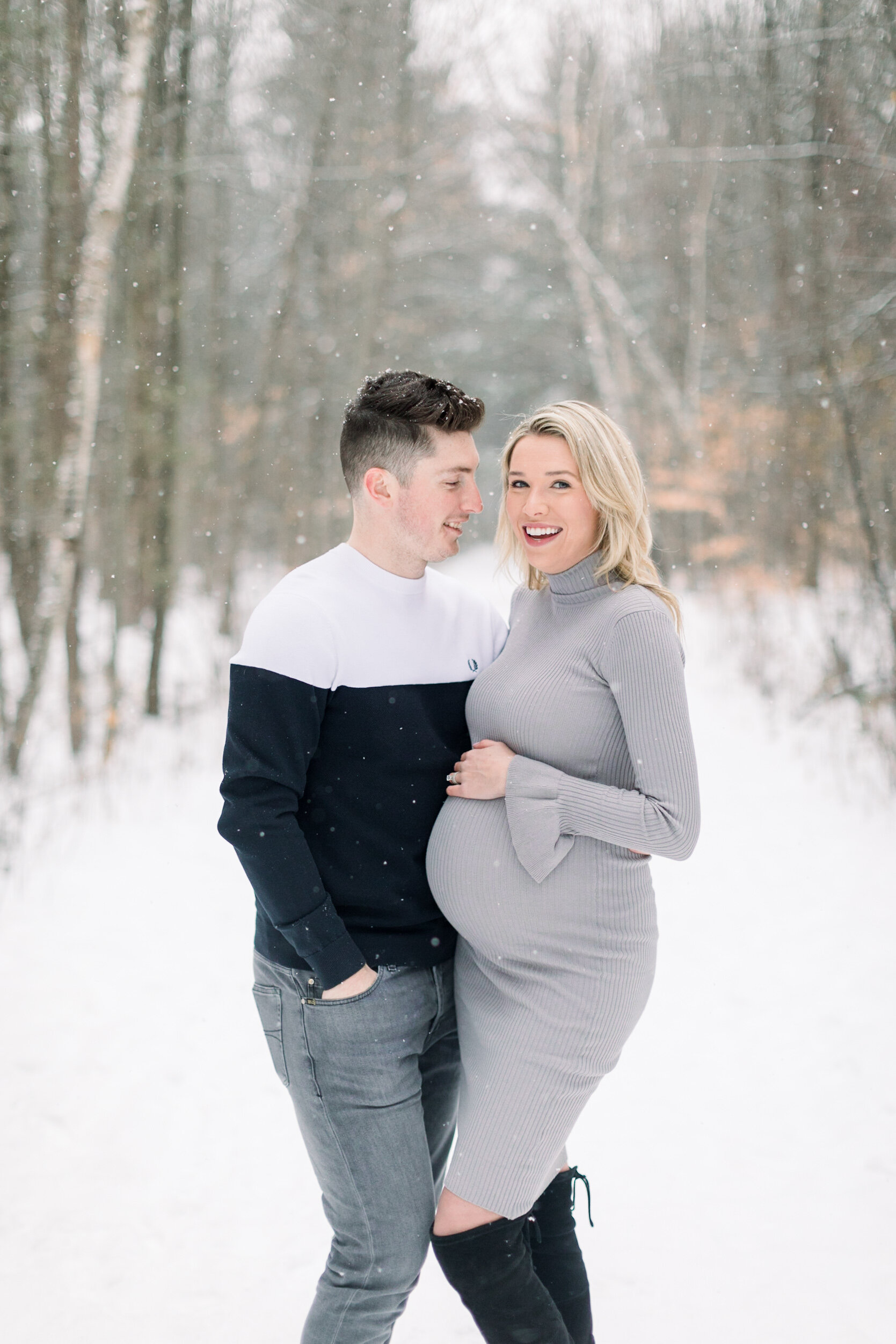  A handsome husband looks at his glowing wife as she holds her pregnant belly in a soft and romantic Ottawa winter maternity photo shoot by professional photographer Chelsea Mason Photography. Couple goals maternity goals maternity outfit inspiration