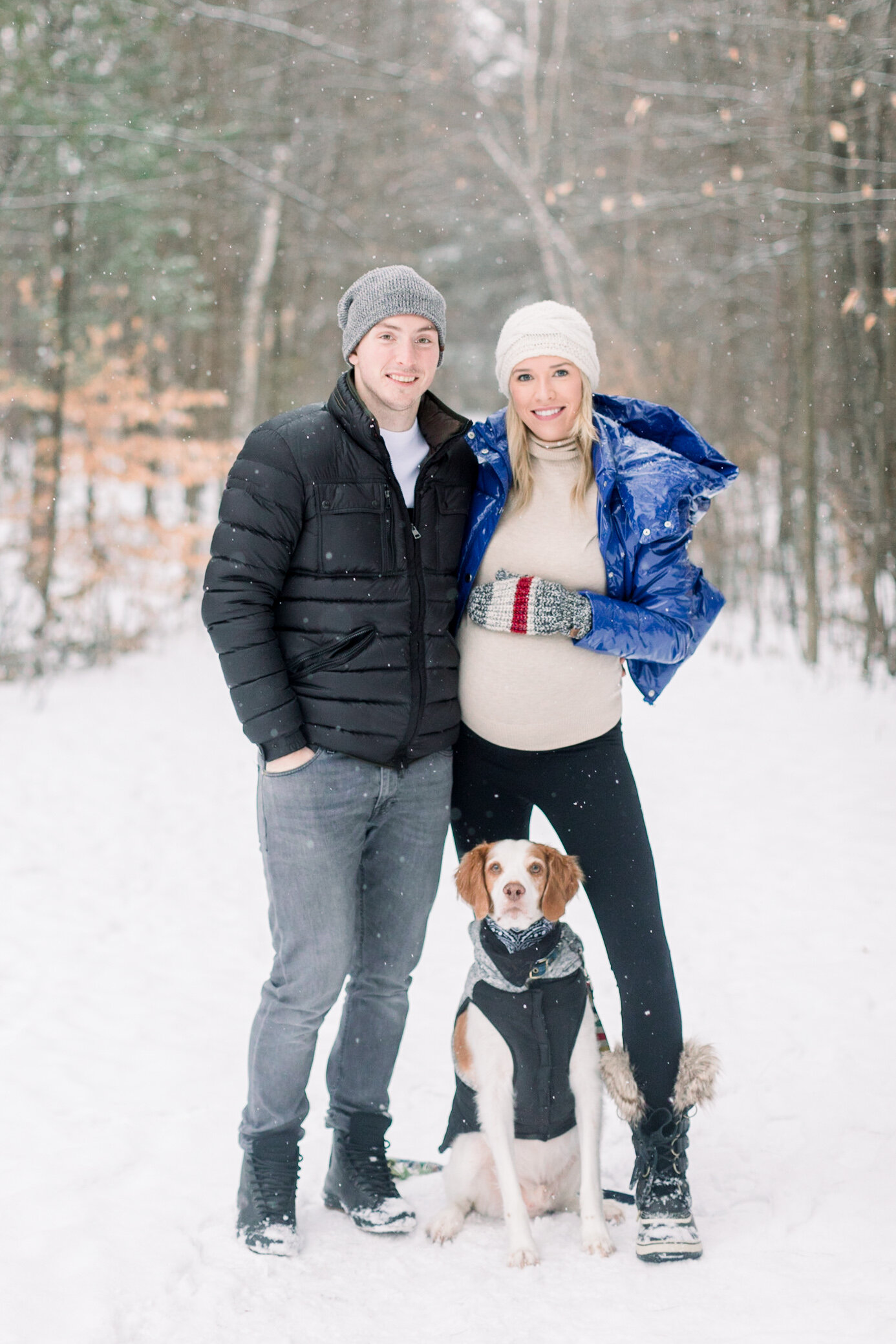  A beautiful little family stand in the snow as she cradles her baby bump in snow covered Pinhey’s Trail In Ottawa. Maternity session goals winter maternity session couple goals puppy goals outdoor photo shoot inspiration ideas and goals winter clien