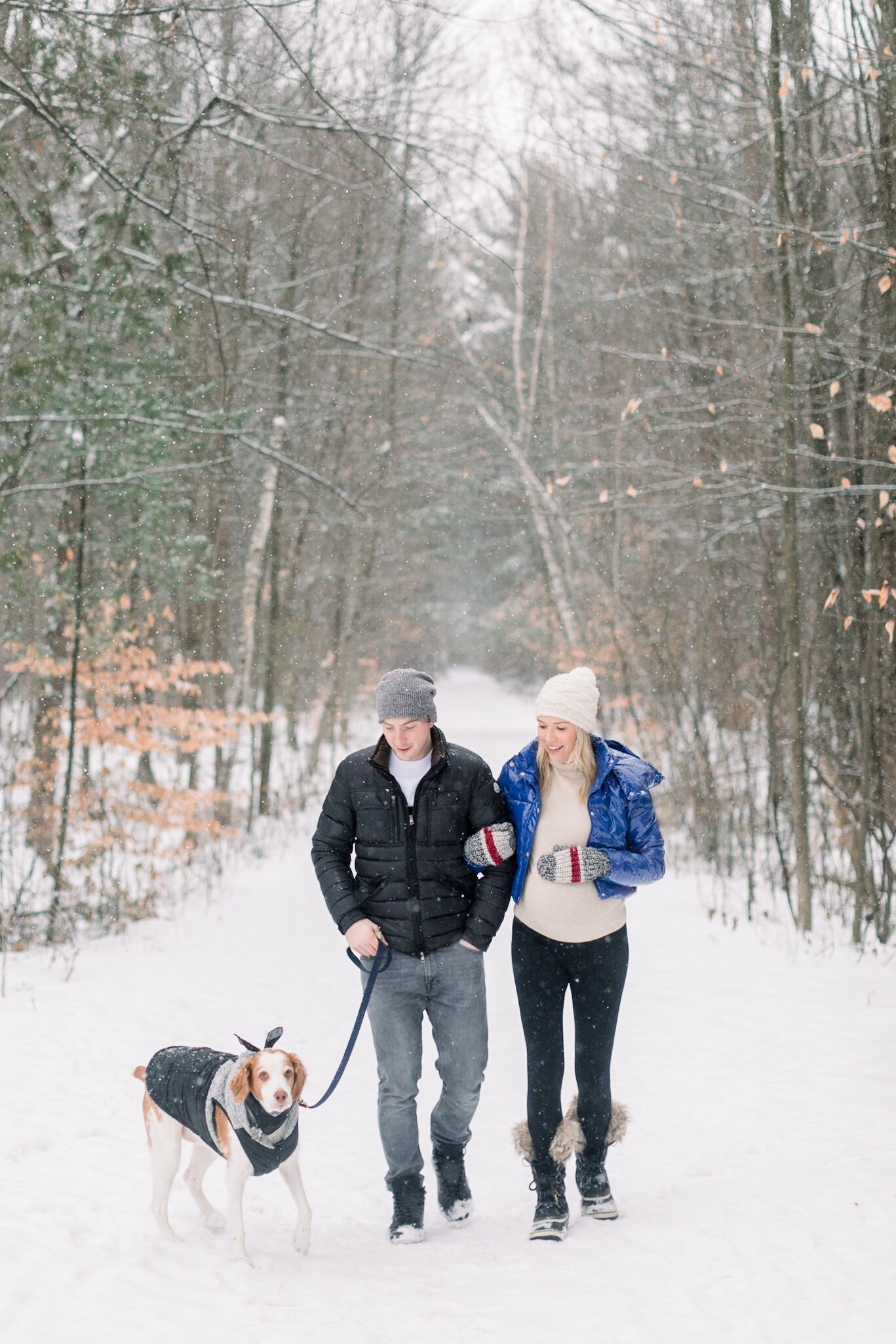  A beautiful pregnant family walk their dog in the Pinhey Trails in Ottawa in a winter wonderland by Chelsea Mason Photography. Couple goals family goals maternity session pose inspiration ideas and goals client attire inspiration for winter outdoor 