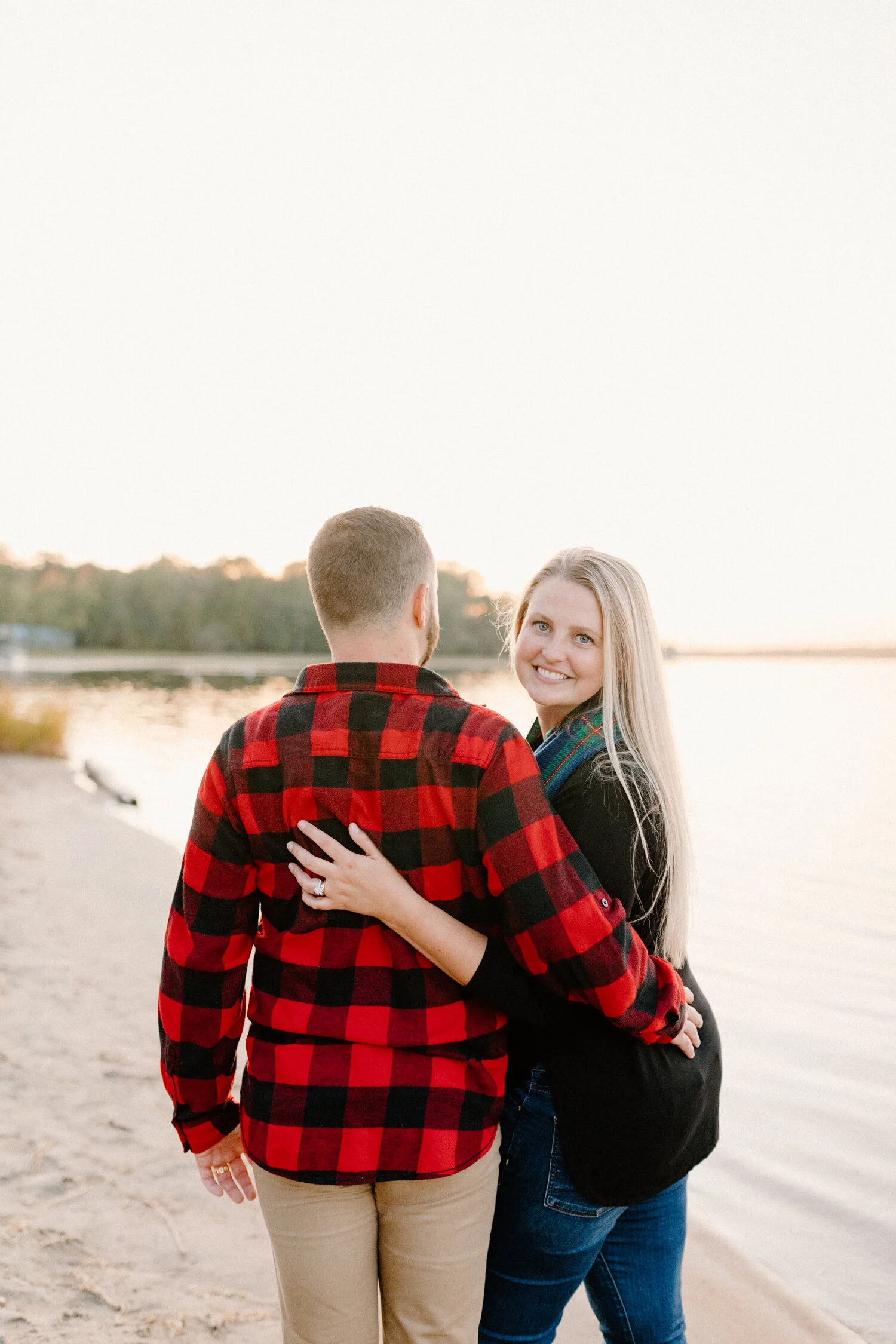  While walking along the shoreline at Constance Bay Beach, Chelsea Mason Photography captures this couple walking with their arms wrapped around one another. Girl looks backwards while walking along beach, romantic sunset canadian beach engagement se