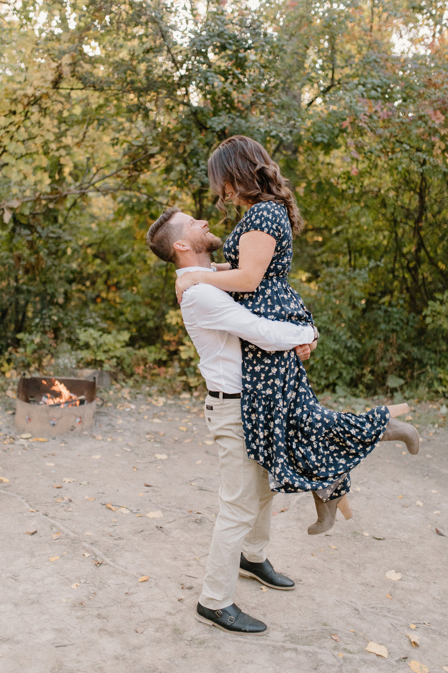  During this wooded camping engagement session in Ontario, Canada, Chelsea Mason Photography captures this soon-to-be groom holding his fiance and leaning in for a kiss. Camping engagement session, campfire engagement session, formal engagement sessi