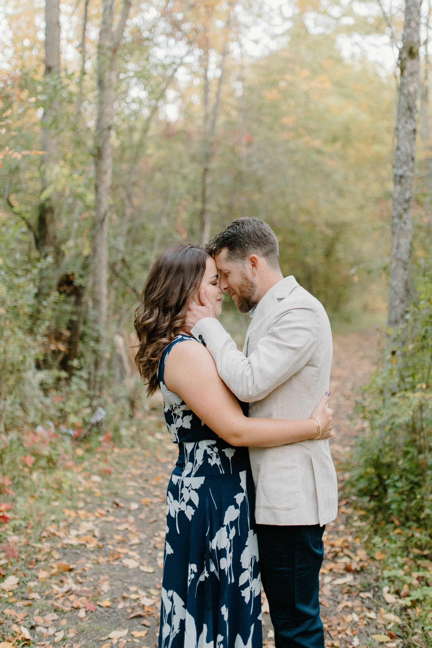  Chelsea Mason Photography captures this Ottawa, Canada couple romantically embracing and pressing foreheads together during this wooded camping engagement session. Wooded autumn engagement session, wooded dirt pathway engagement location, womens for
