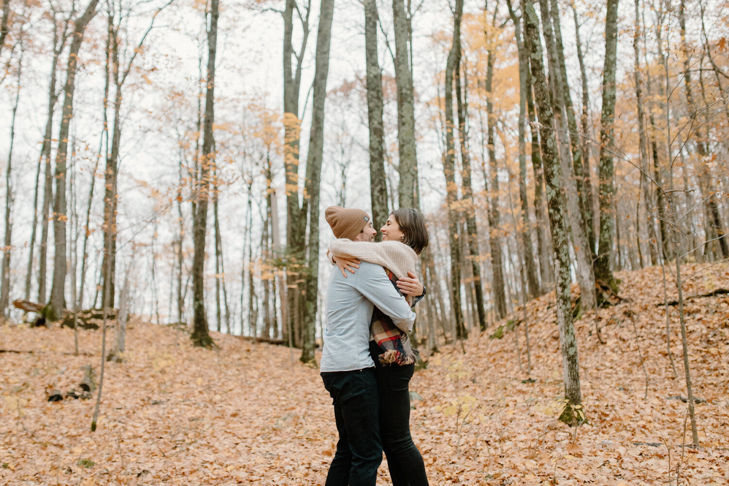  Wrapped in one another’s arms, Chelsea Mason Photography captures this in-love couple during their engagement shoot in Quebec, Canada. Couple wrapped in one another’s arms, man picking up wife, nice casual autumn engagement outfit, womens cream over