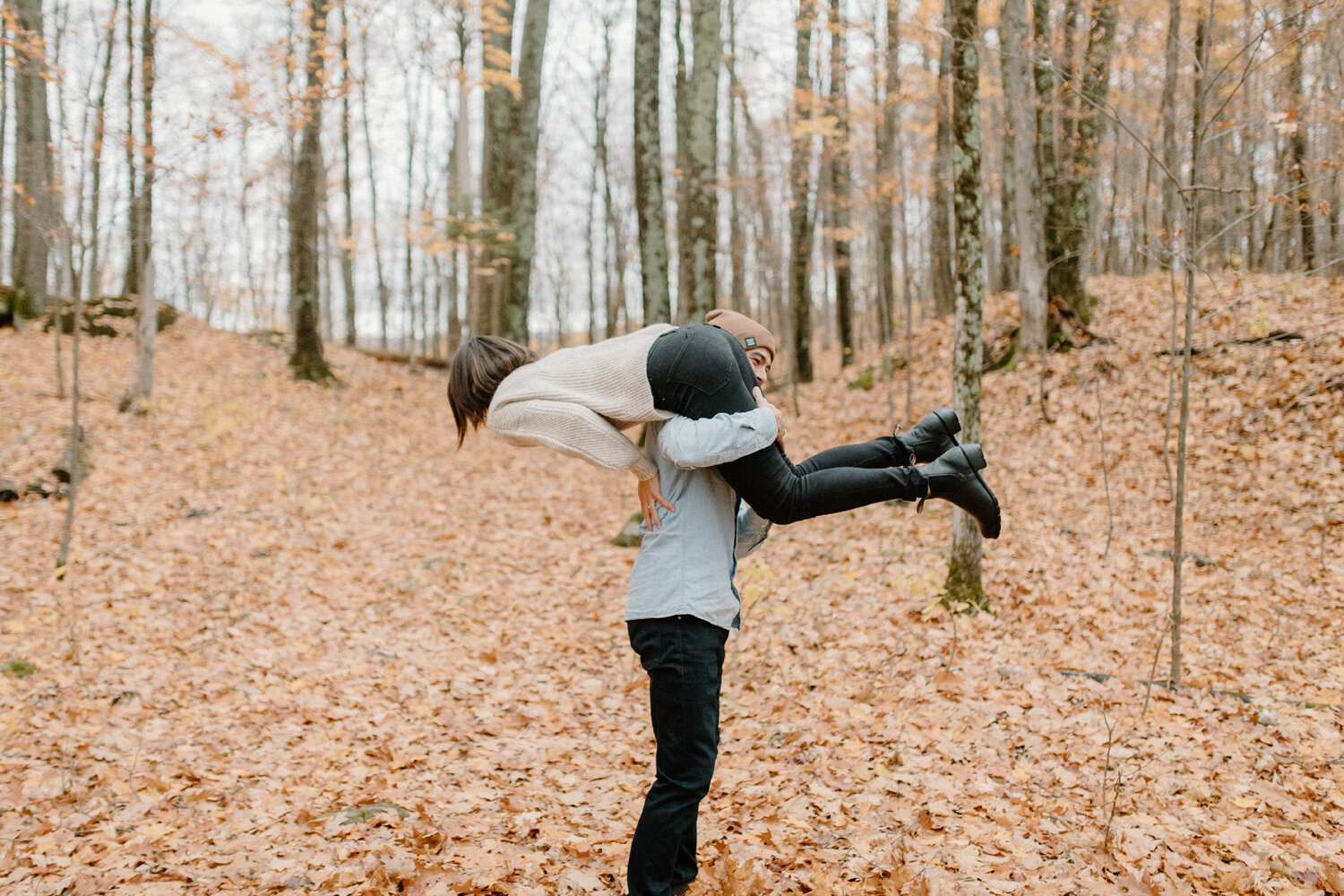  During this playful engagement session in the forrest near Quebec, Canada, Chelsea Mason Photography captures this soon-to-be groom lift and carry his fiance over his shoulder. Laughing engagement photos, silly engagement poses, man lifting woman, a