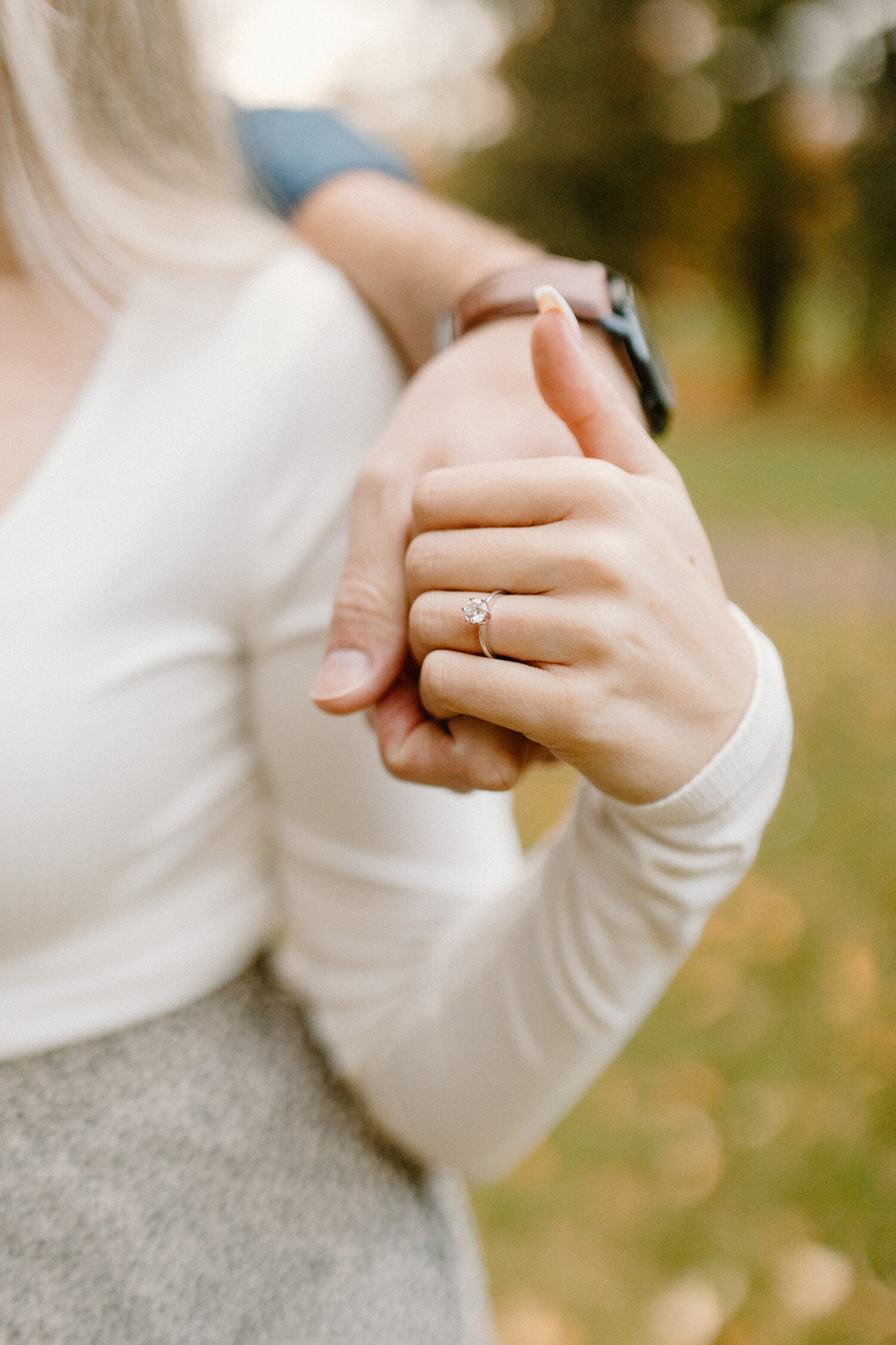  During their autumn engagement session in Quebec, Canada, Chelsea Mason Photography captures an up-close detailed shot of this engaged couple holding hands and flaunting her engagement ring. white gold solitaire diamond engagement ring, engaged coup
