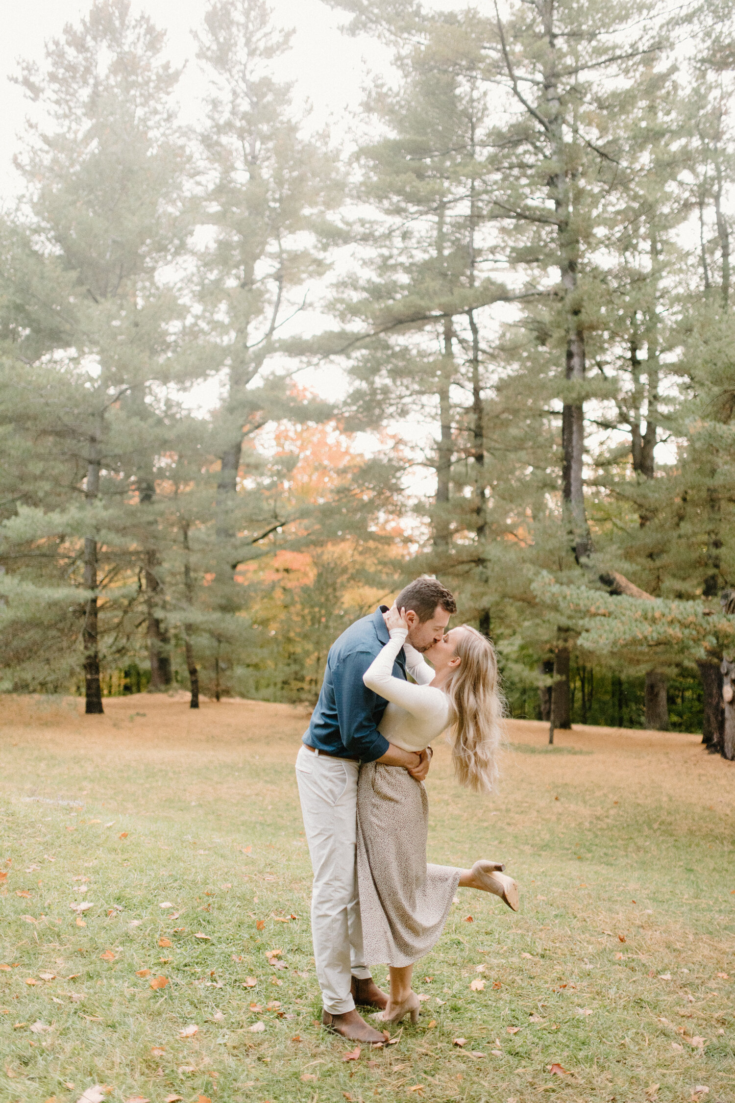  With autumn leaves falling in the backdrop, Chelsea Mason Photography captures a romantic, dramatic kiss between this couple during their engagement session in Quebec, Canada. passionate dramatic kissing, neutral engagement outfits, long loose curle