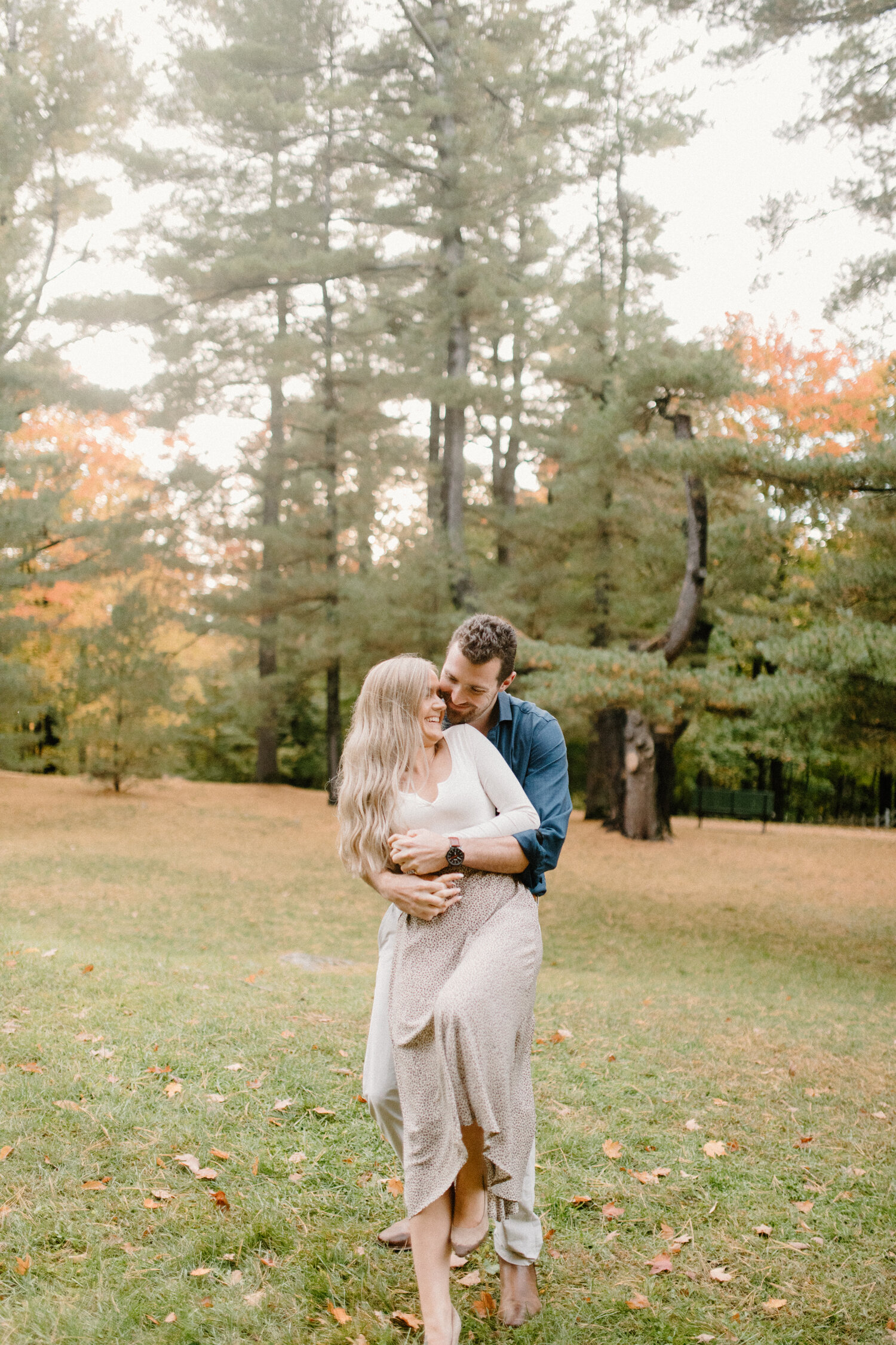  Playfully hugging his fiance from behind, Quebec Canada photographer, Chelsea Mason Photography captures a playful moment between this couple. playful engagement session, man hugging fiance from behind, neutral engagement outfit colors, autumn coupl
