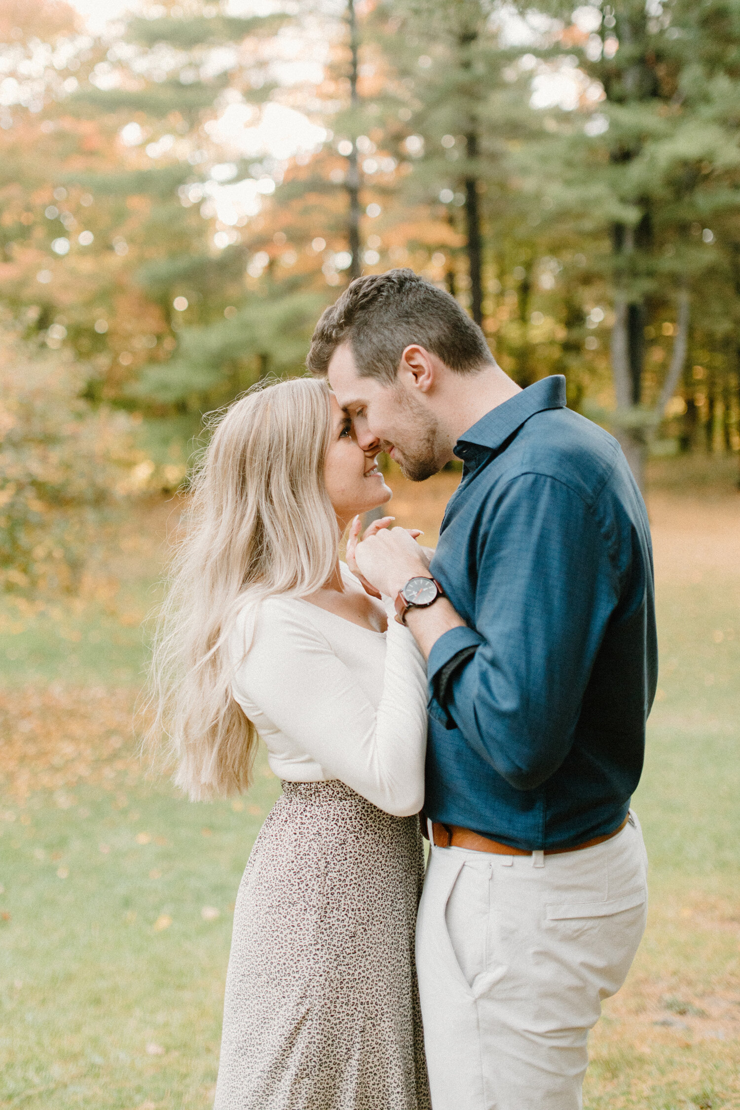  With orange autumn leaved blurred in the backdrop, Chelsea Mason Photography captures this Quebec, Canada couple holding hands and romantically pressing their foreheads against one another. neutral colored formal engagement outfits, womens leopard p