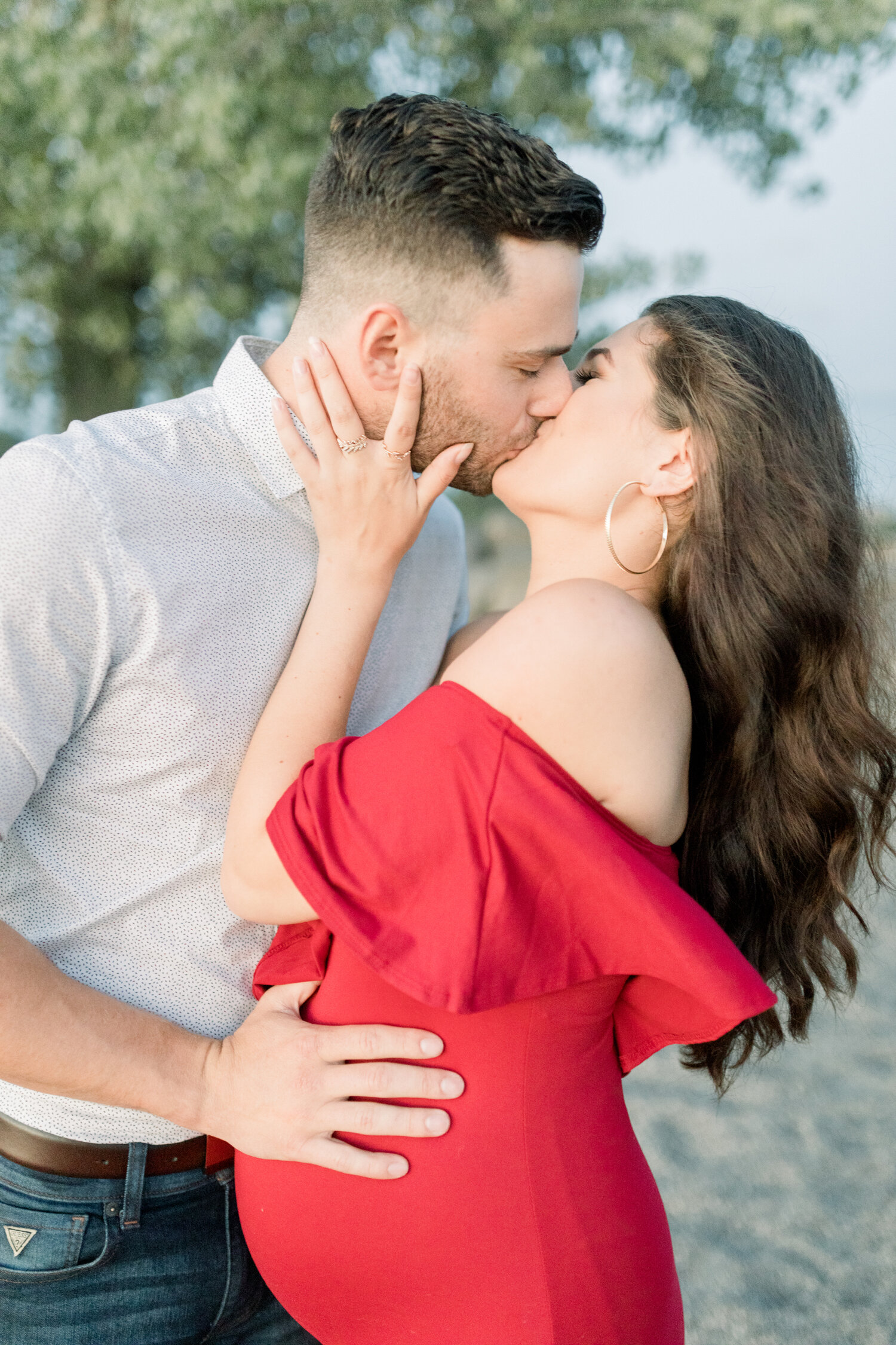  During this maternity shoot along Brittania Beach in Ottawa, Canada, Chelsea Mason Photography captures this expectant couple share a passionate kiss. sunset maternity beach session, ottawa canada maternity photographer, red off the shoulder fitted 