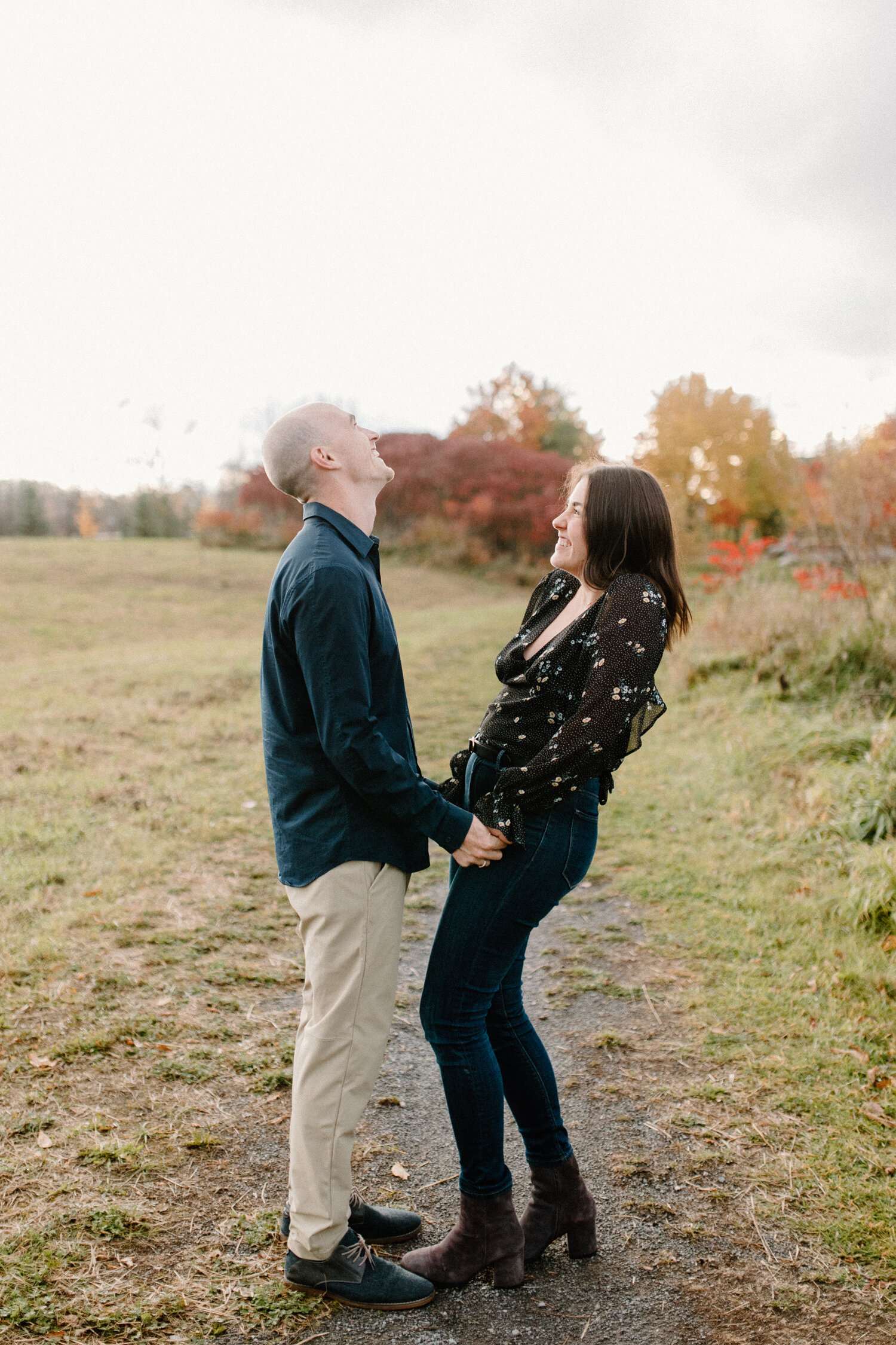  This Ontario, Canada couple pose playfully while laughing and holding hands during their engagement session with Chelsea Mason Photography. khaki and black colored engagement outfits, autumn engagement outfit, couple holding hands, playful engagemen