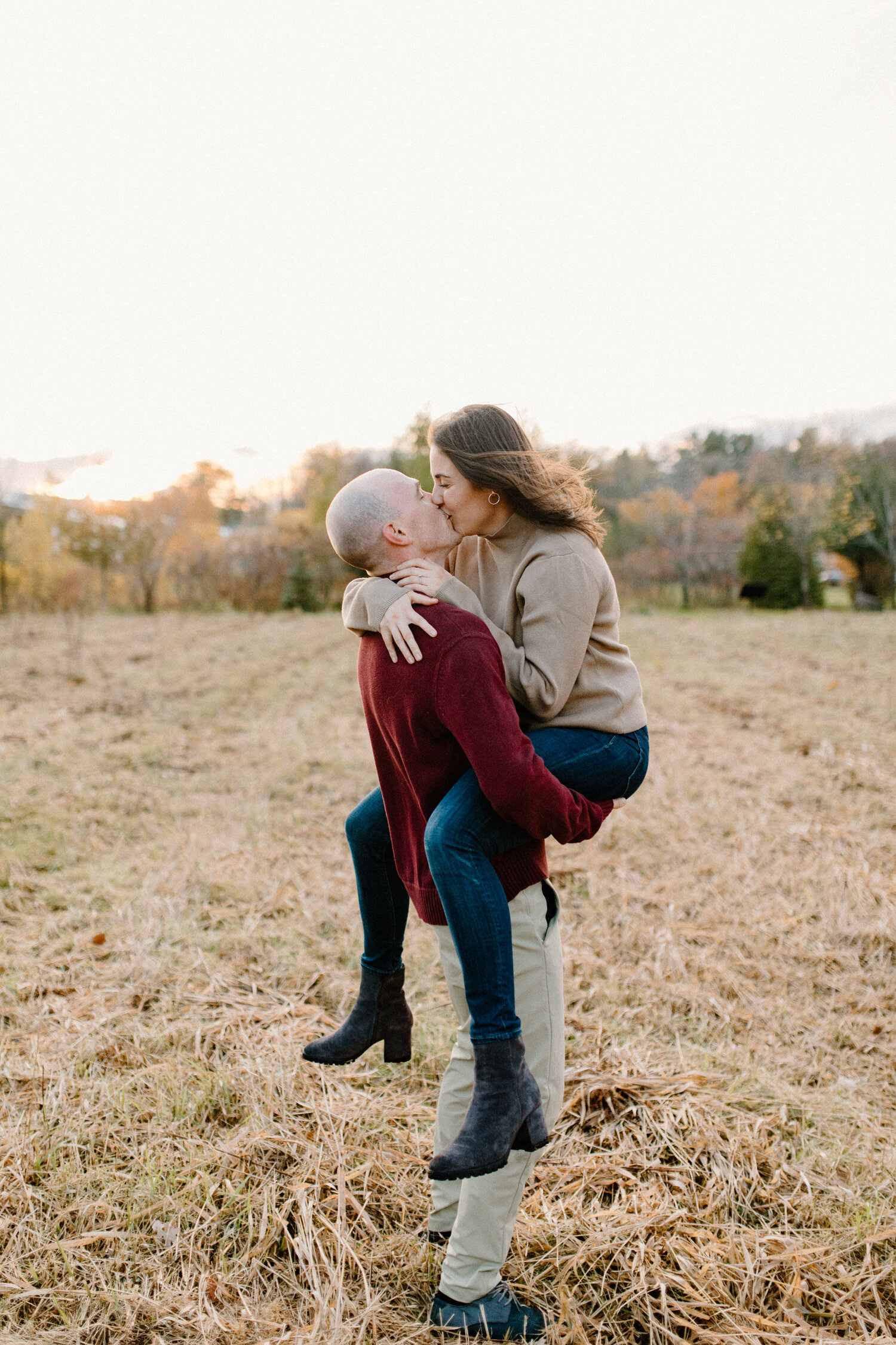  Posed in an open grass field, on an overcast day, Chelsea Mason Photography captures this groom holding his fiance and leaning in for a kiss during their engagement session in Ottawa, Canada. autumn ottawa canada engagement session groom holding fia