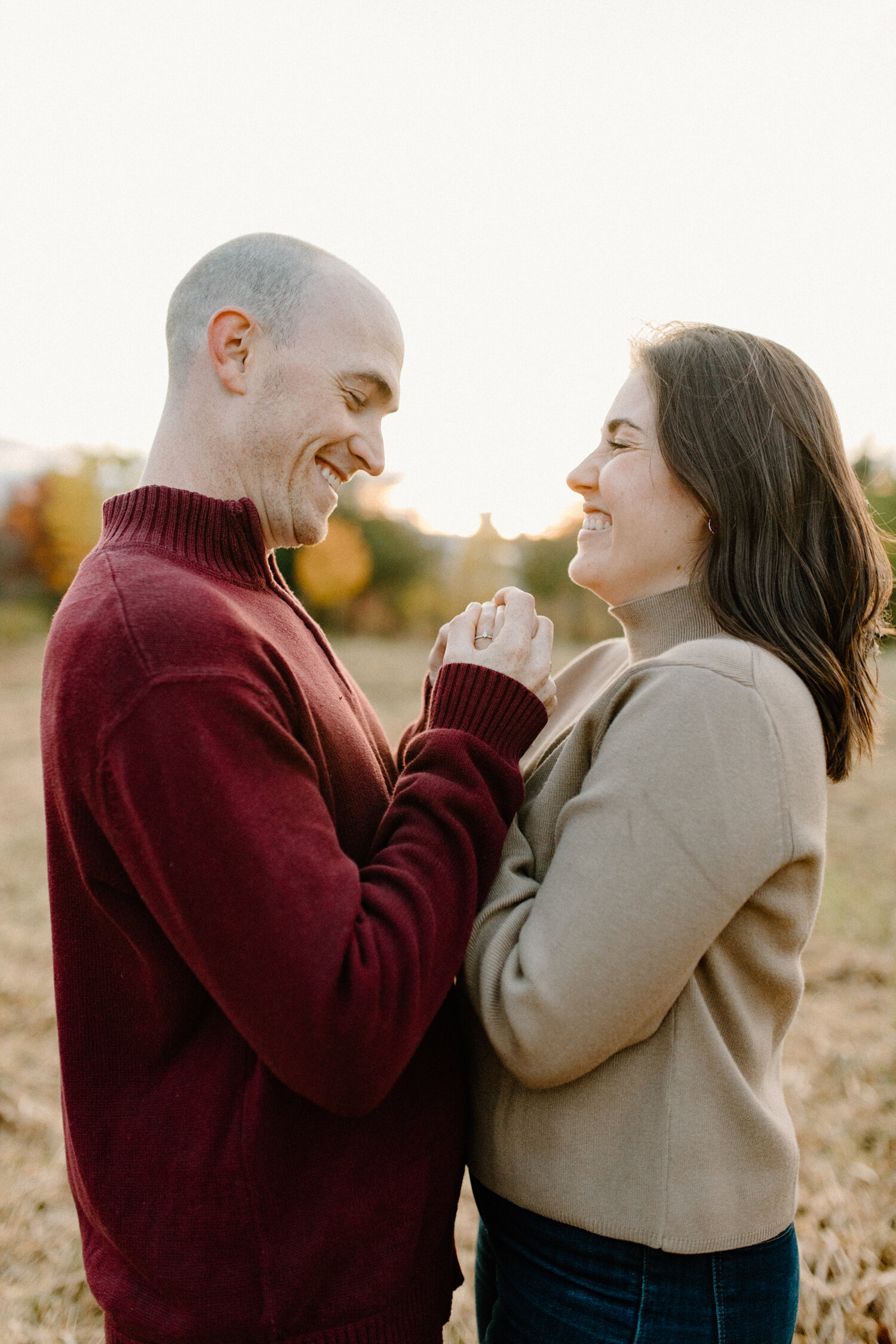  Laughing playfully, Ontario, Canada’s Chelsea Mason Photography captures this couple holding hands and smiling during their autumn engagement session. womens mock neck turtle neck sweater mens red pullover ontario canada engagement photographer bare