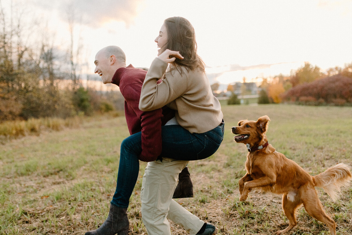  While her groom gives her a piggyback ride, Chelsea Mason Photography captures this couple’s family dog running along beside them during their engagement session in Ontario, Canada. medium brown colored golden retriever dog included in engagement se