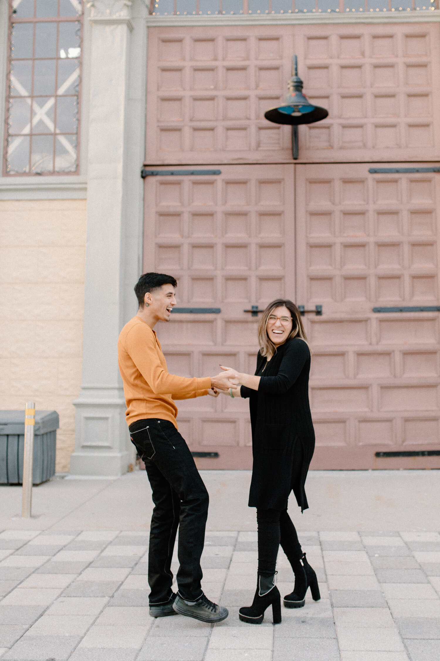  Outside of Ottawa, Canada’s Horticulture Building, Chelsea Mason Photography captures this laughing engaged couple holding hands. womens all black outfit womens ombre medium length shoulder length hair couple holding hands ottawa canada engagement p