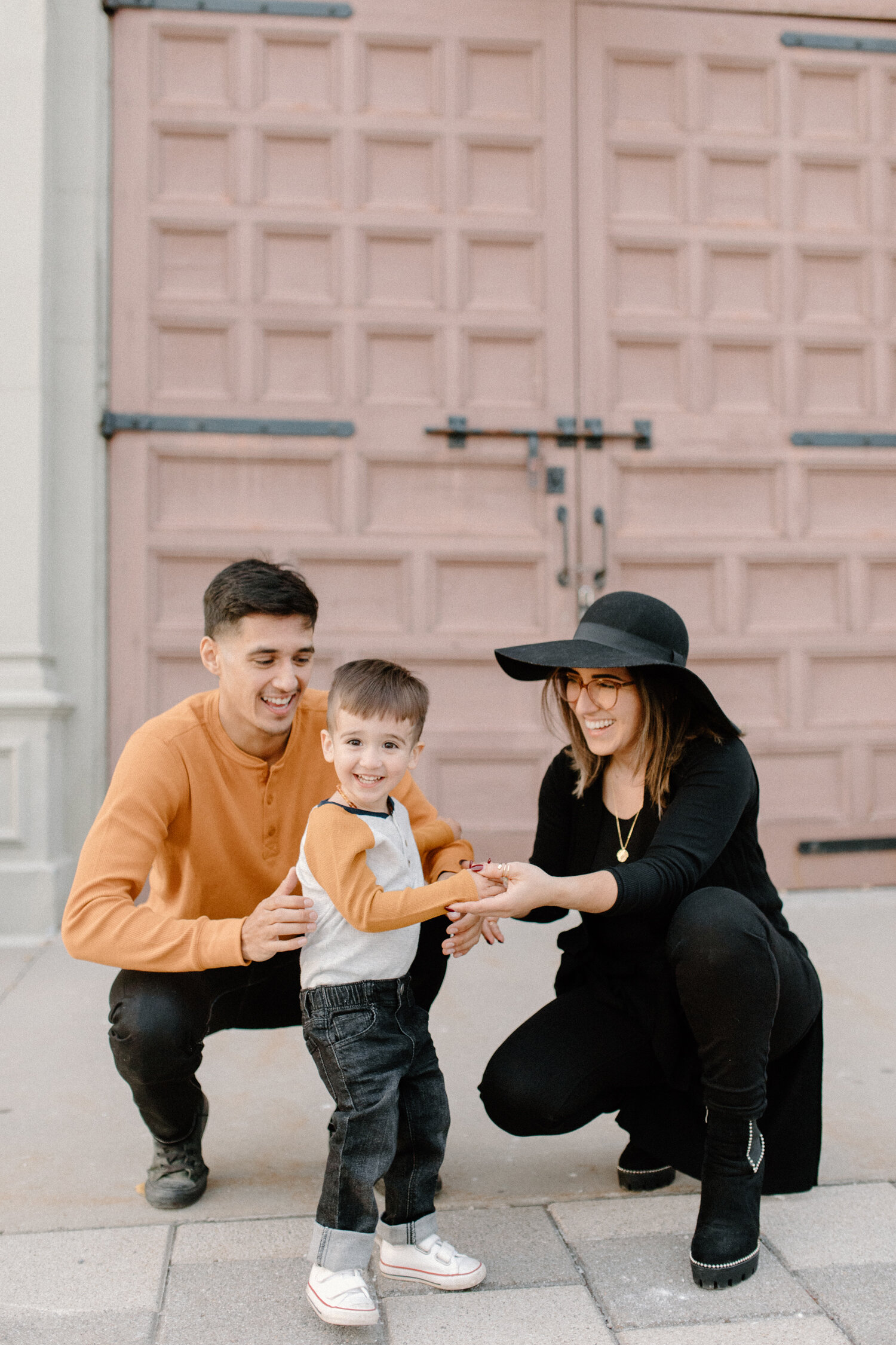  Ontario, Canada’s Chelsea Mason Photography captures this family of three holding hands and smiling during their family photo session. ontario canada family photographer orange and black family outfit colors photos urban ottawa canada engagement ses