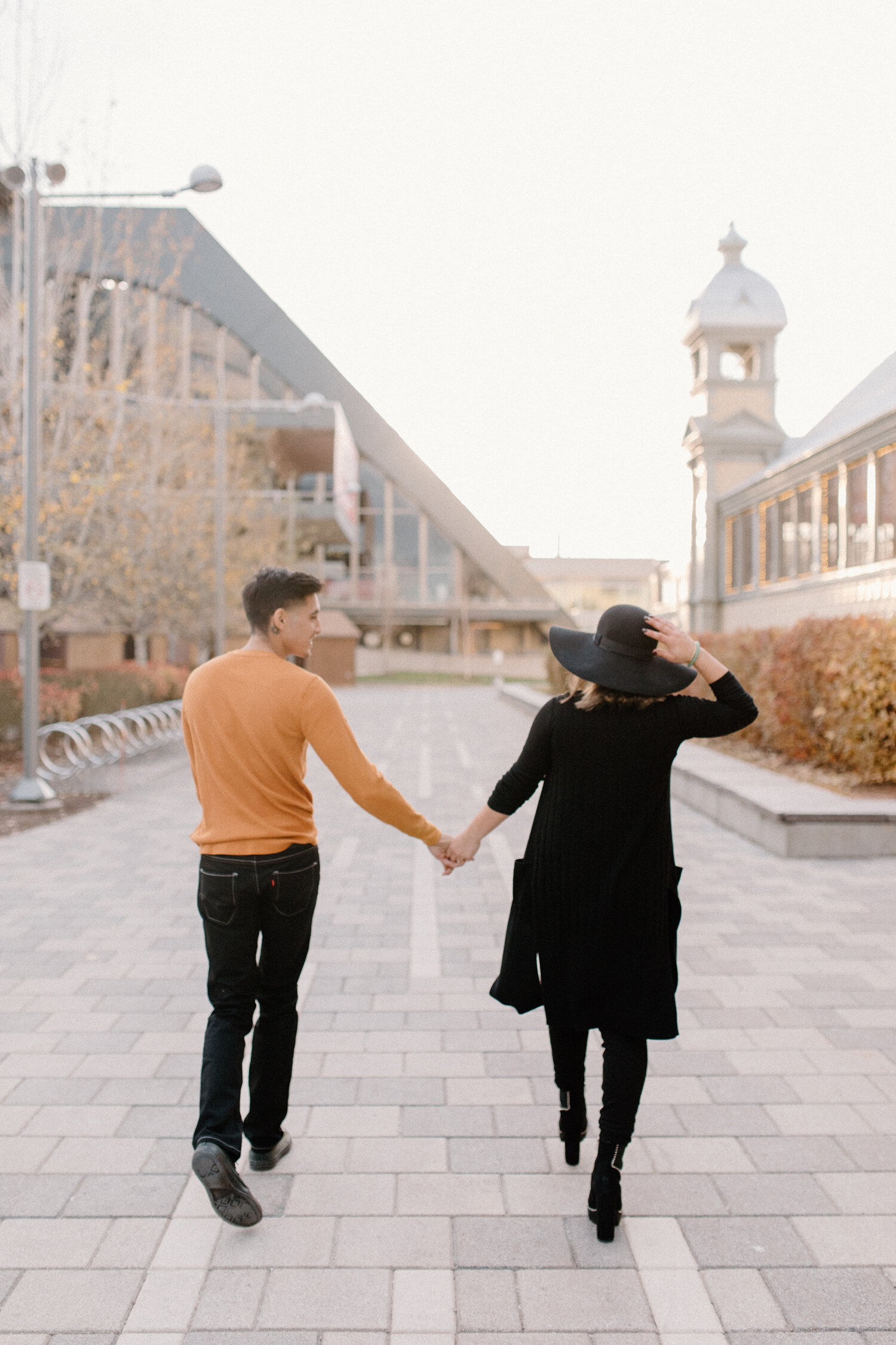  Walking outside of Ottawa, Canada’s Horticulture Building, Chelsea Mason Photography captures this couple holding hands. couple walking and holding hands orange and black family photo color scheme womens black suede knee high boots womens black hat 