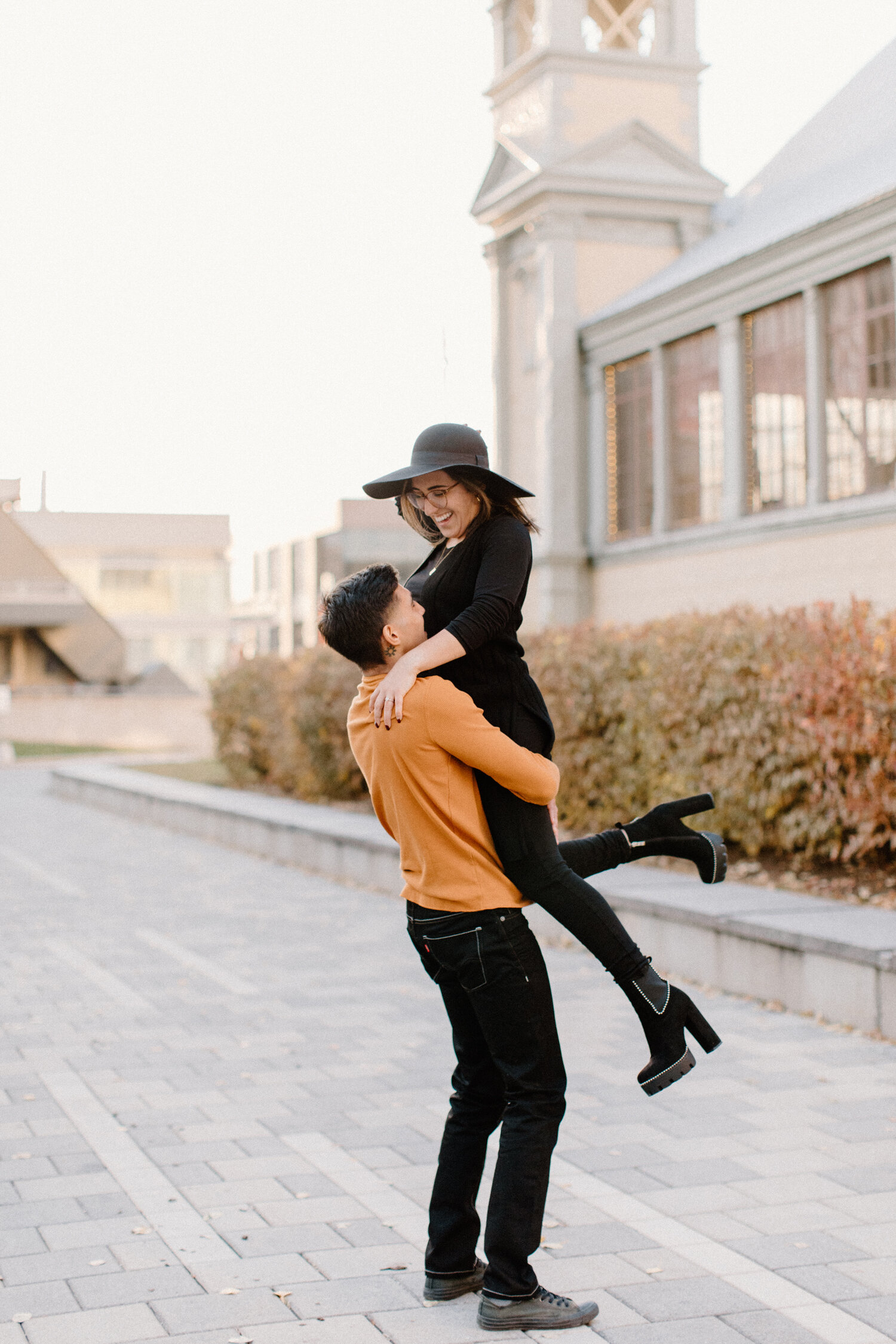  Standing outside Ottawa, Canada’s Horticulture Building, Chelsea Mason Photography captures this man carrying his fiance playfully. ottawa canada engagement photographer womens tall block heeled suede black bootie all black womens outfit black women