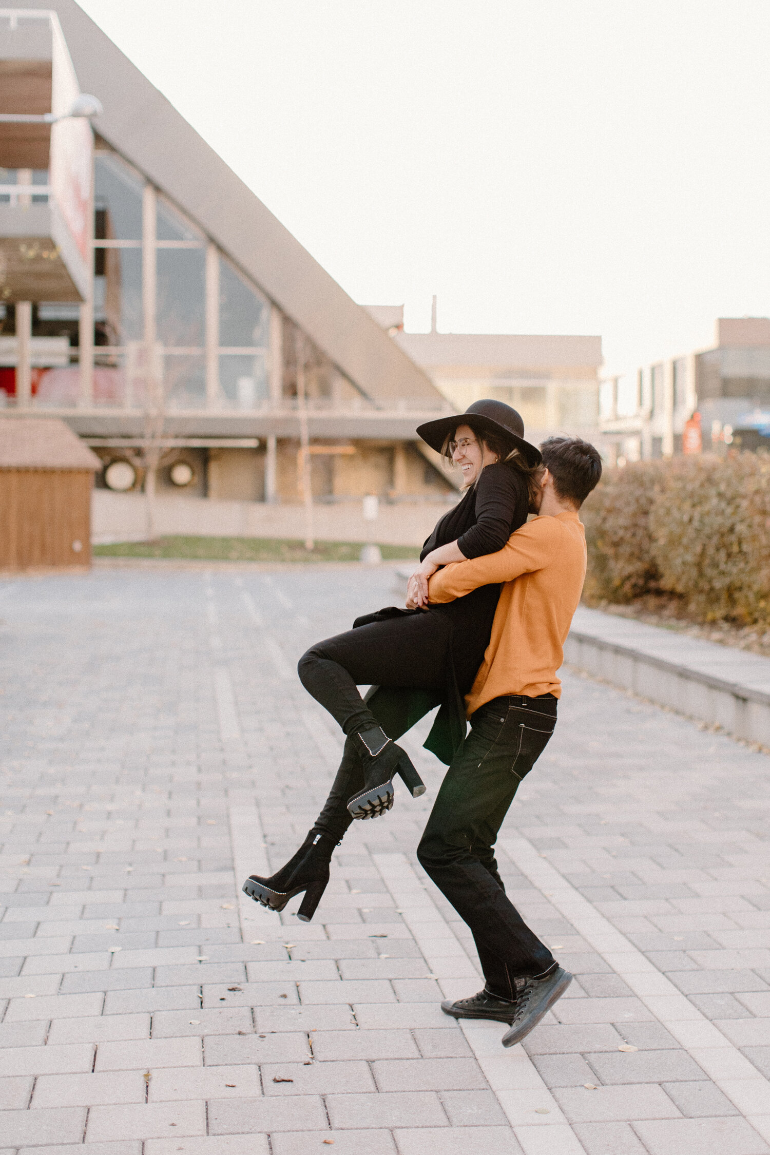  During this couples session in Ontario, Canada, Chelsea Mason Photography captures this man holding and spinning his fiance. ontario canada engagement photographer couples photographs playful engagement session black and orange couples outfit colors