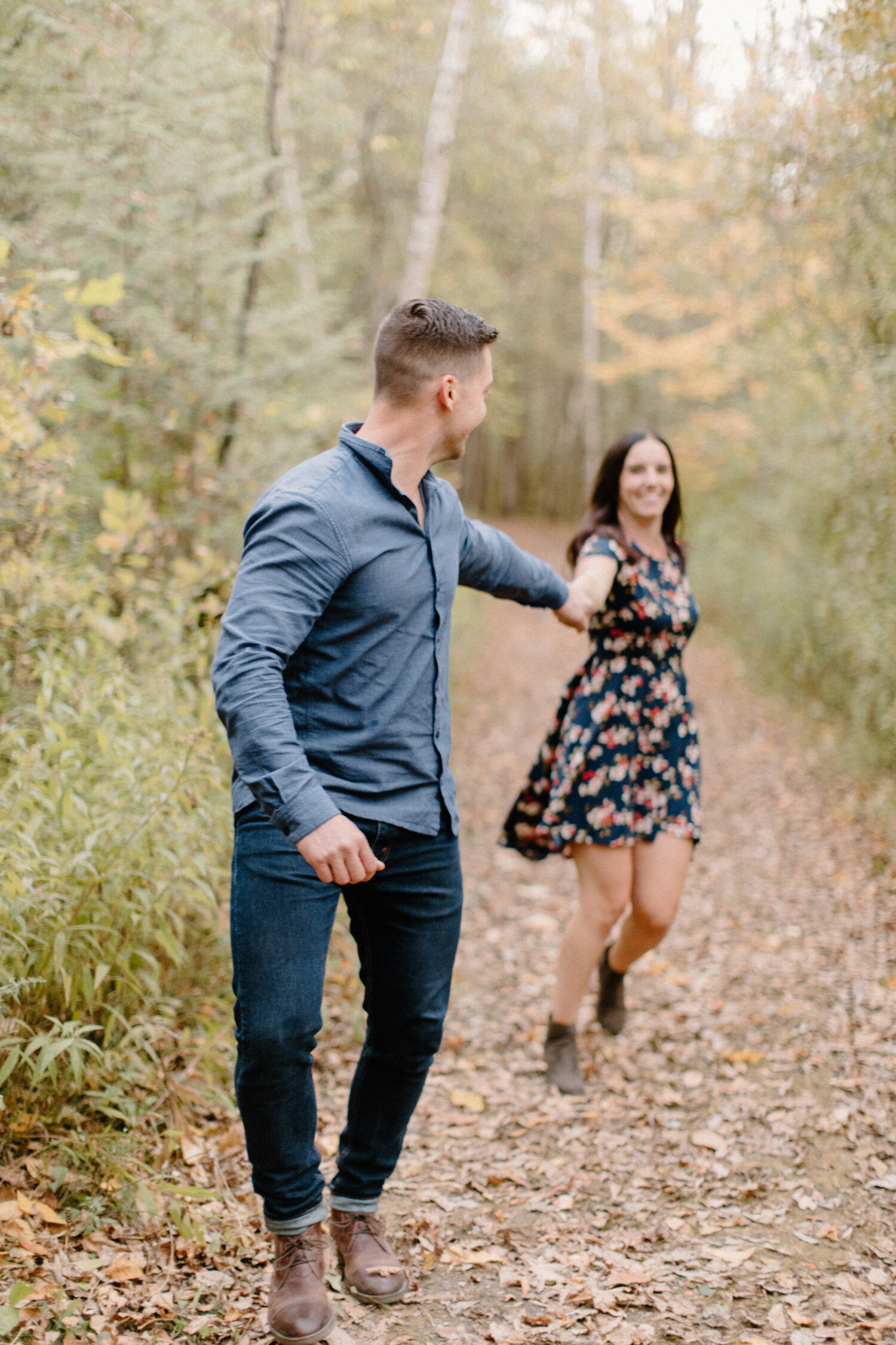  While taking their engagement photos on an unpaved autumn leaf filled path, Chelsea Mason Photography captures this man leading his fiance by the hand in Brockville, Ontario. brockville ontario engagement photographer autumn engagement session women