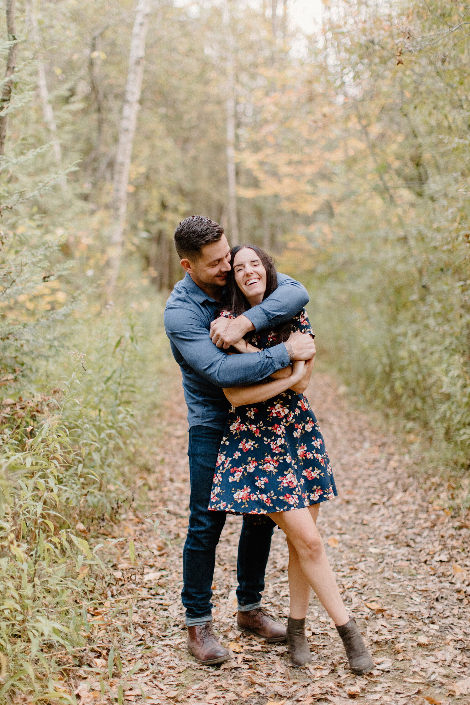  Chelsea Mason Photography captures a playful moment between this engaged couple as they wrap their arms around one another and laugh during this photo session in Brockville, Ontario. wooded pathway brockville ontario autumn engagement session photos