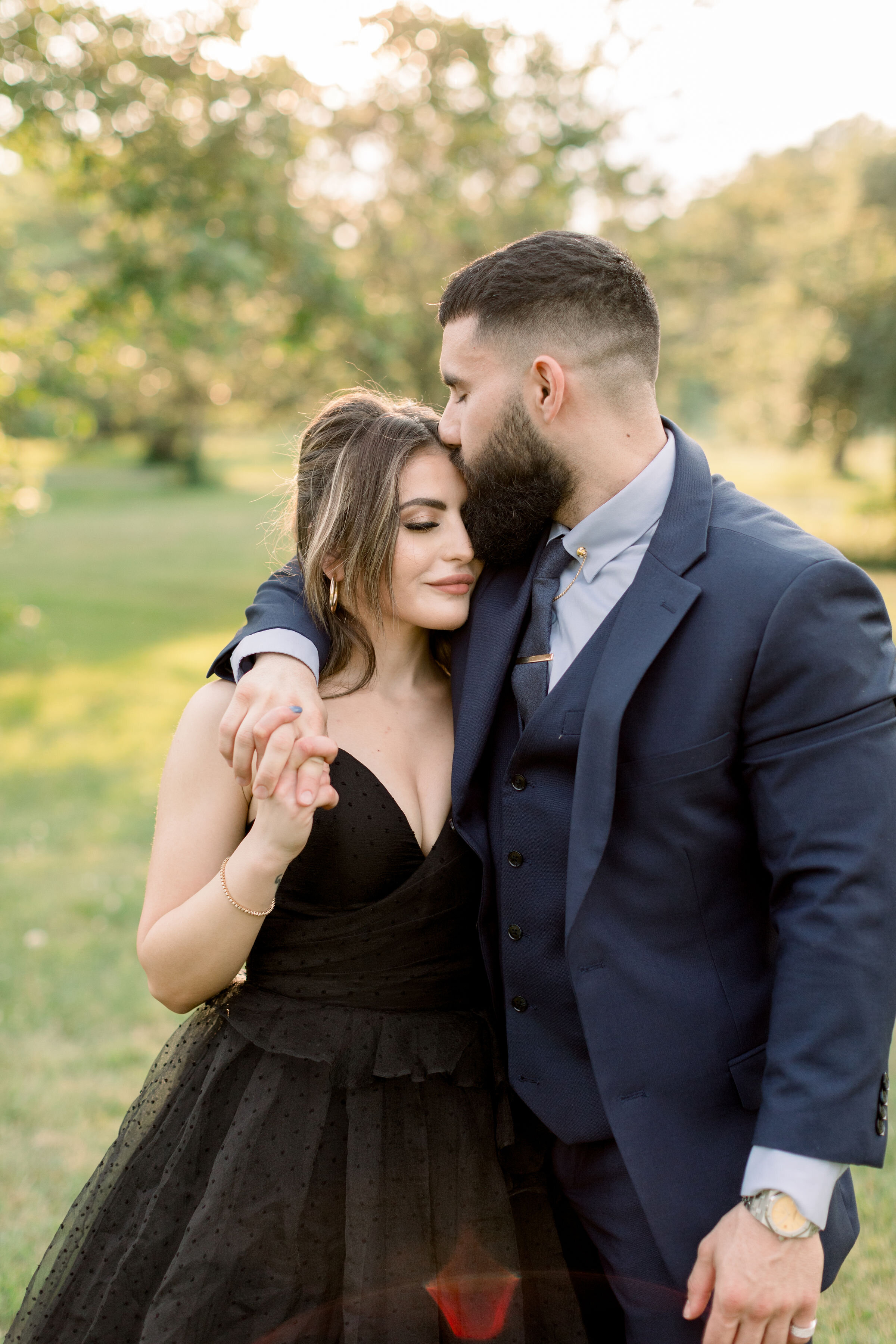  During this park engagement session in Ottawa, Canada, Chelsea Mason photography captures this couple romantically wrapping their arms around one another while this groom kisses his fiancé's forehead. man kissing woman's forehead romantic couples ph