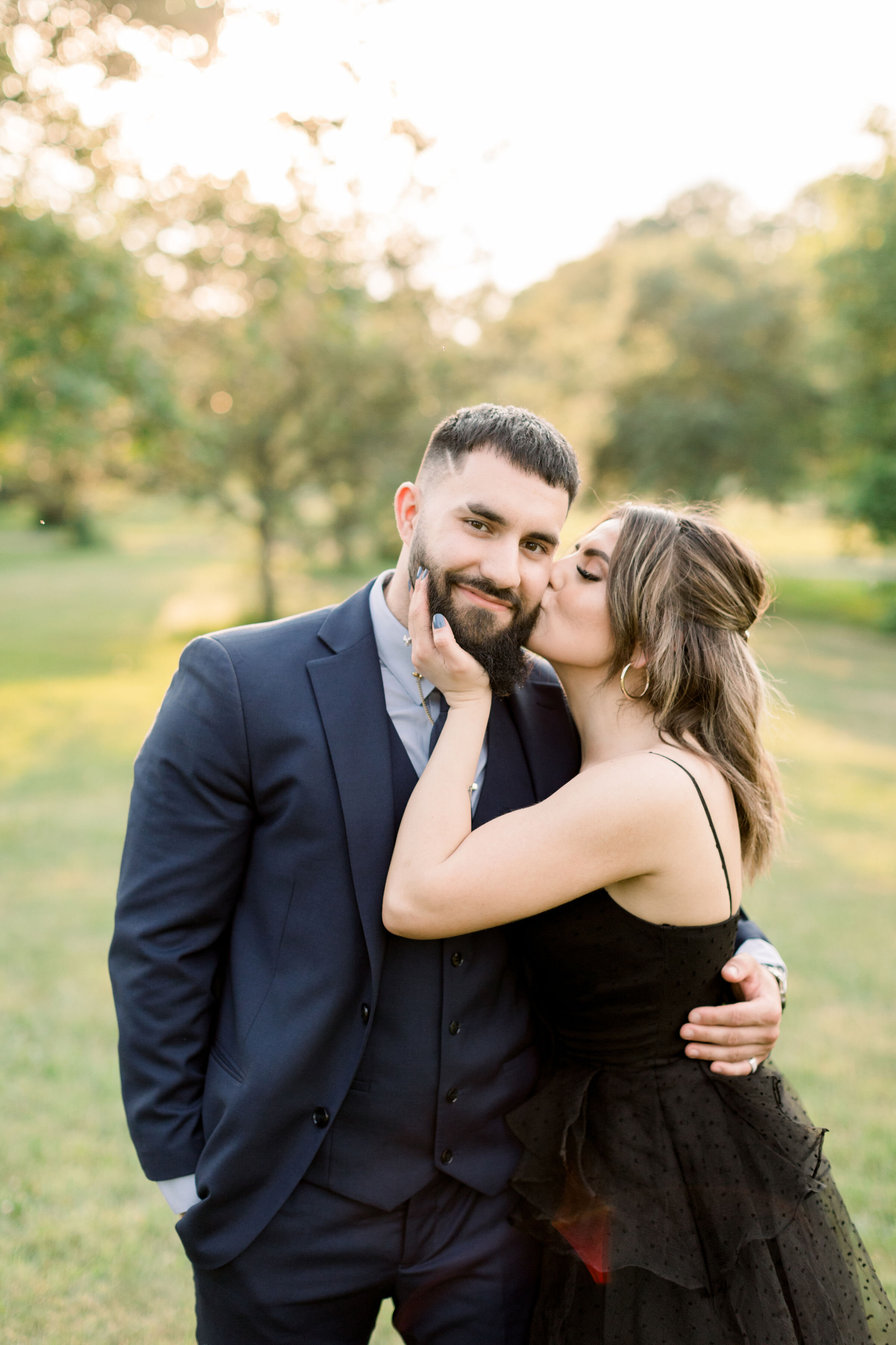  During this park engagement session in Ottawa, Canada, Chelsea Mason photography captures this woman lovingly cupping her fiancé's chin and kissing his cheek. woman kissing man's cheek playful couple poses Ottawa photographer #ChelseaMasonPhotograph