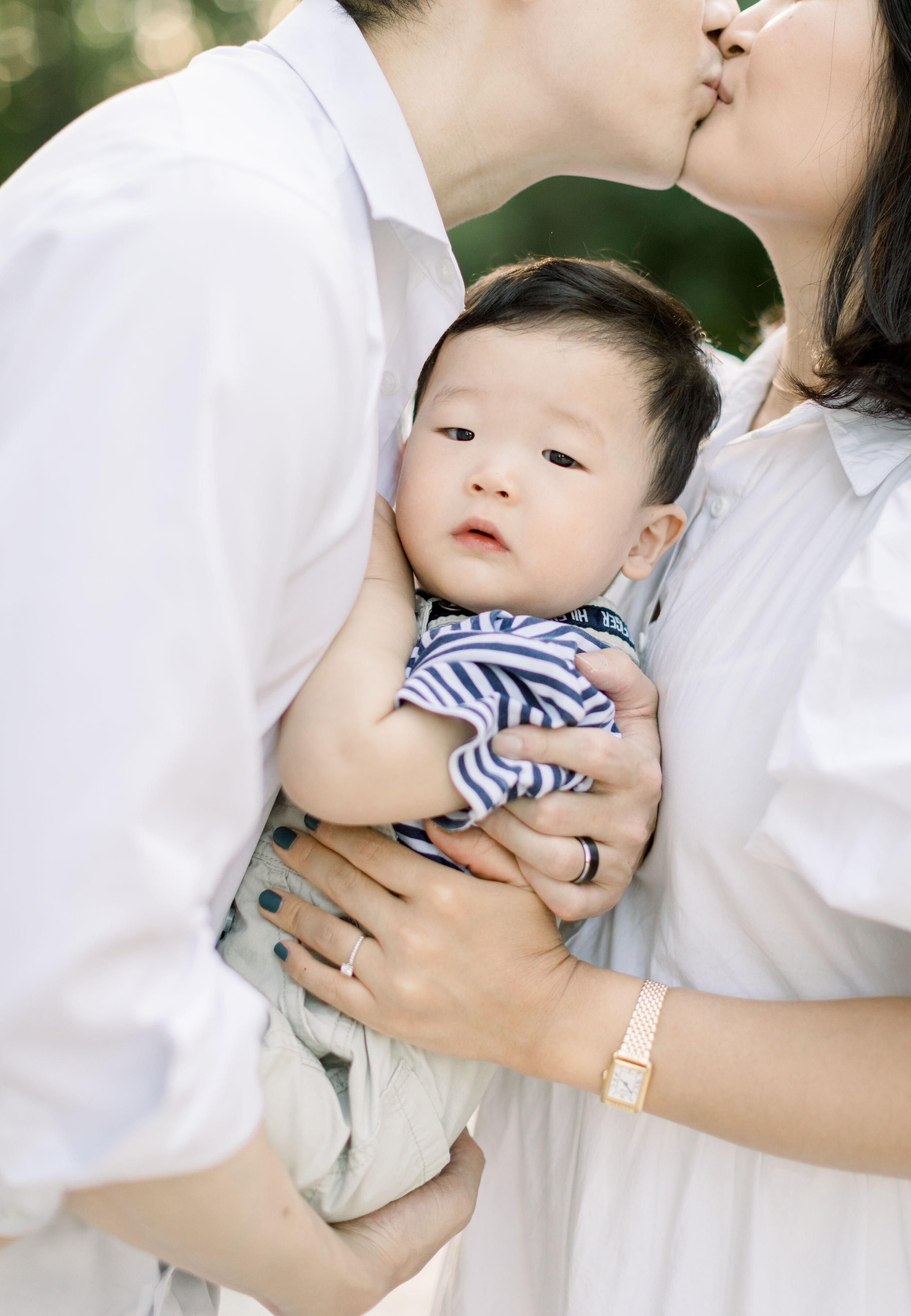  With these parents kissing in the backdrop, Ottawa, Canada family photographer, Chelsea Mason Photography captures an up-close candid photo of this toddler boy. toddler photo with parents kissing in backdrop white family photo outfits womens white t