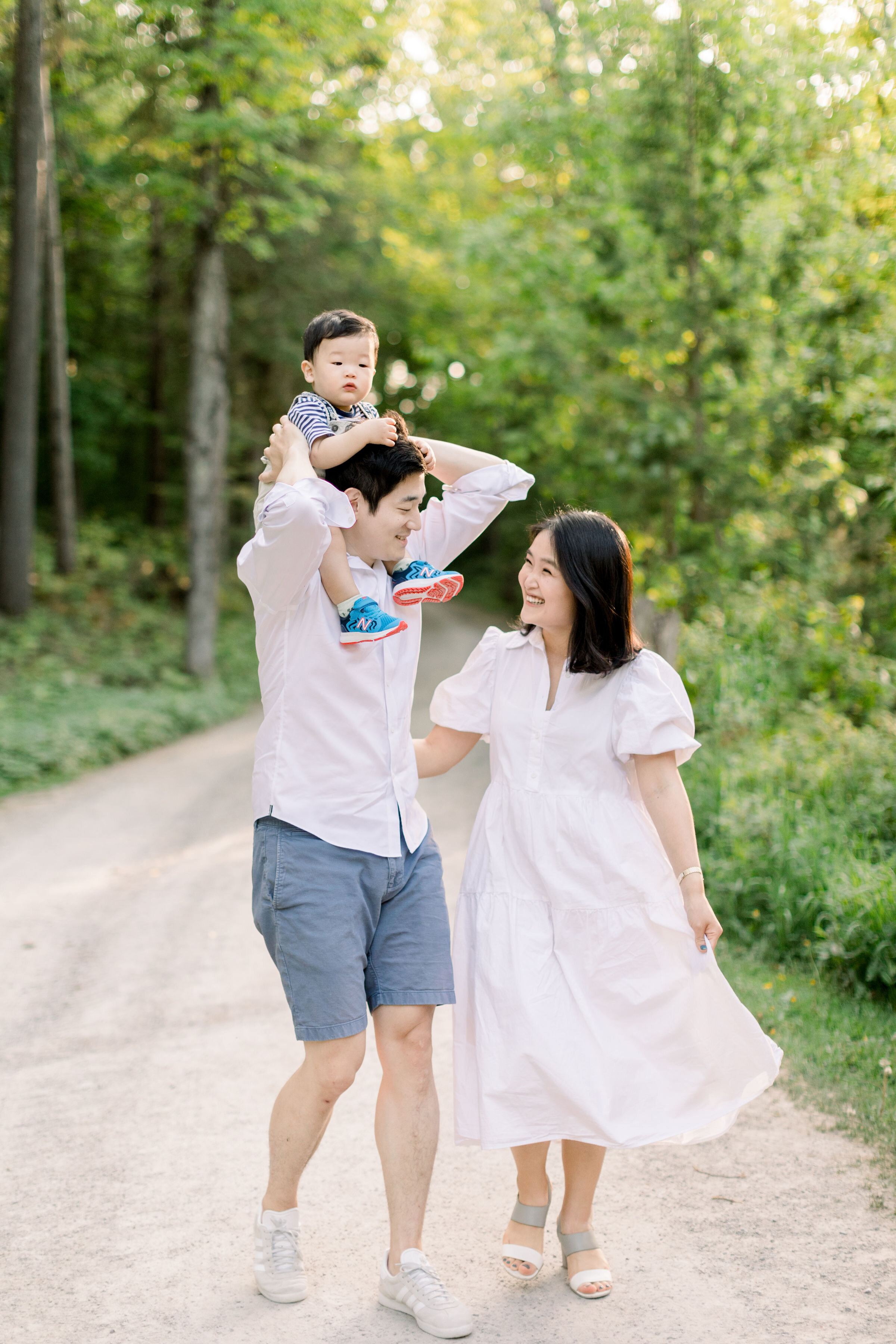  Ottawa, Ontario family photographer, Chelsea Mason photography captures this father giving his toddler son a piggy back ride while his mother walks beside them during this family session. toddler on father's shoulders playful family photo poses Otta