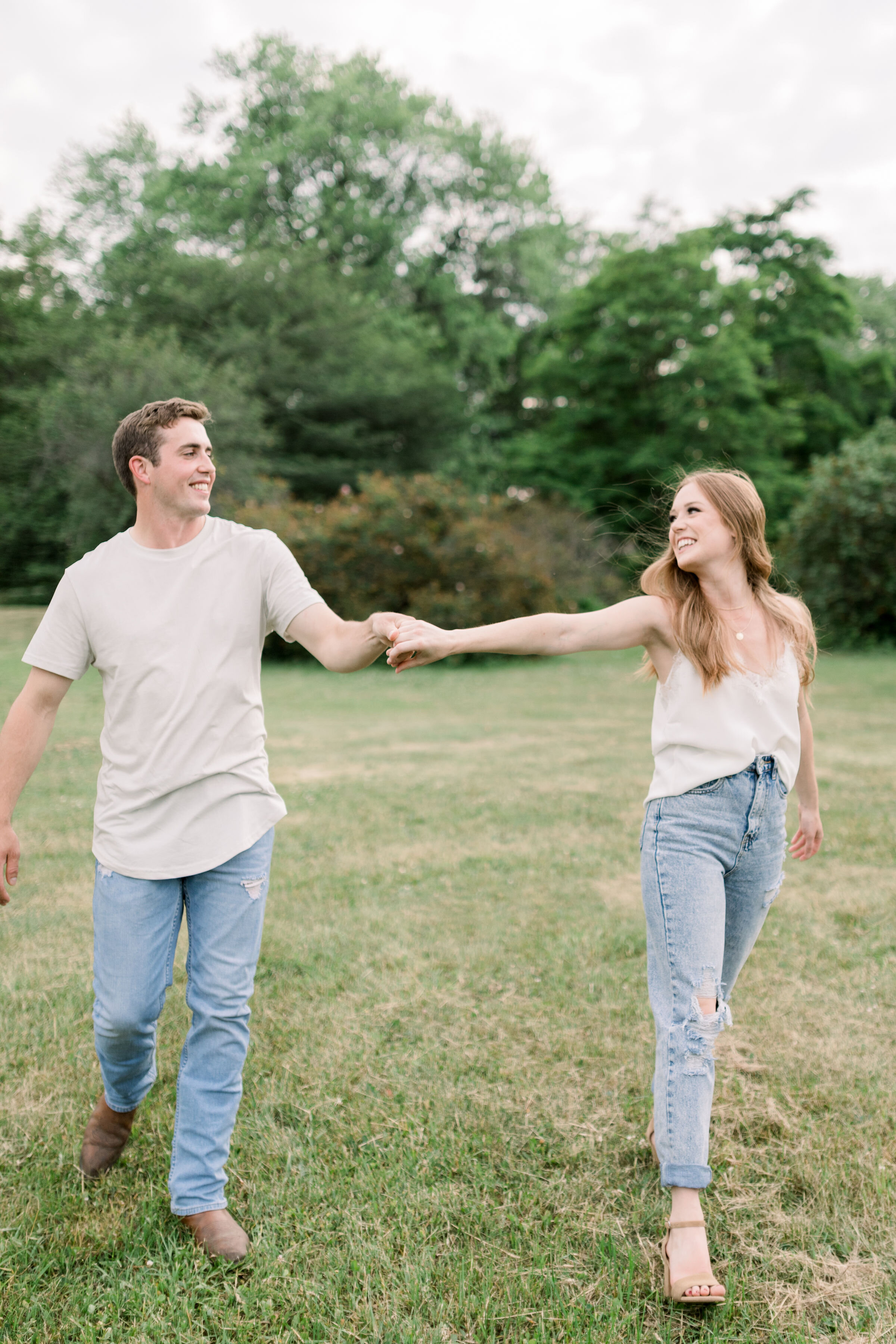  Ottawa, Ontario photographer, Chelsea Mason Photography captures this casually dressed couple walking through a grassy field holding hands. couple holding hands Ottawa couples photographer engagement poses playful #ChelseaMasonPhotography #TheArbore