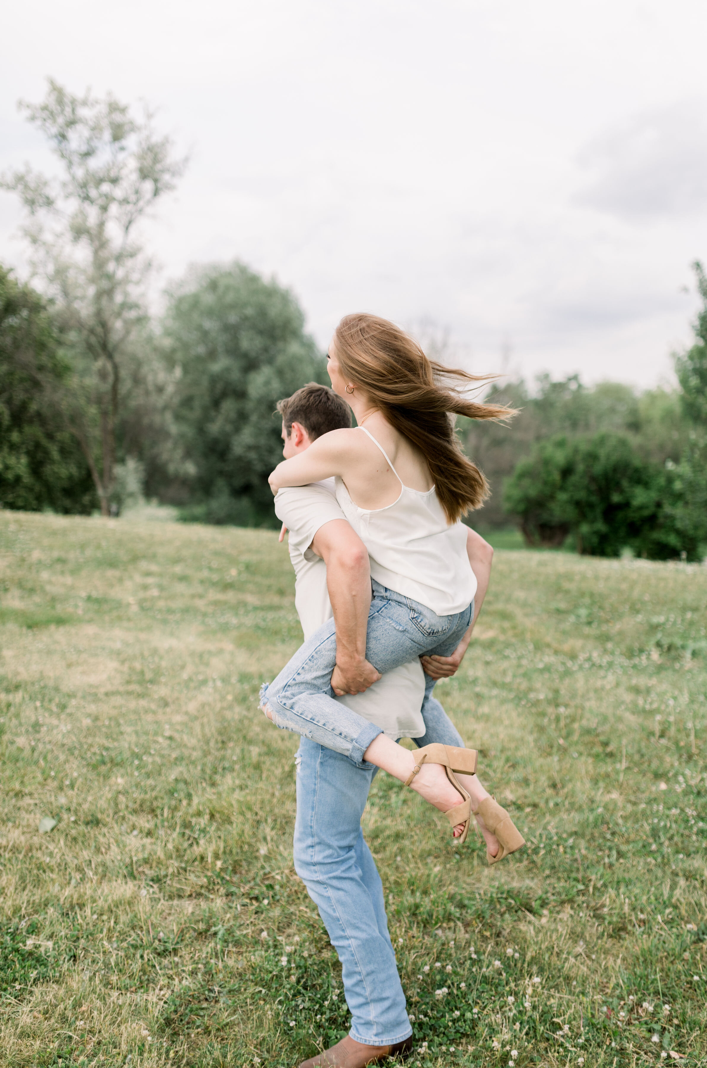  Ottawa, Ontario engagement photographer, Chelsea Mason Photography captures this engaged couple giving one another piggy back rides. piggy back engagement session Ottawa Ontario women's long loose curled auburn hair white shirt and denim pant outfit