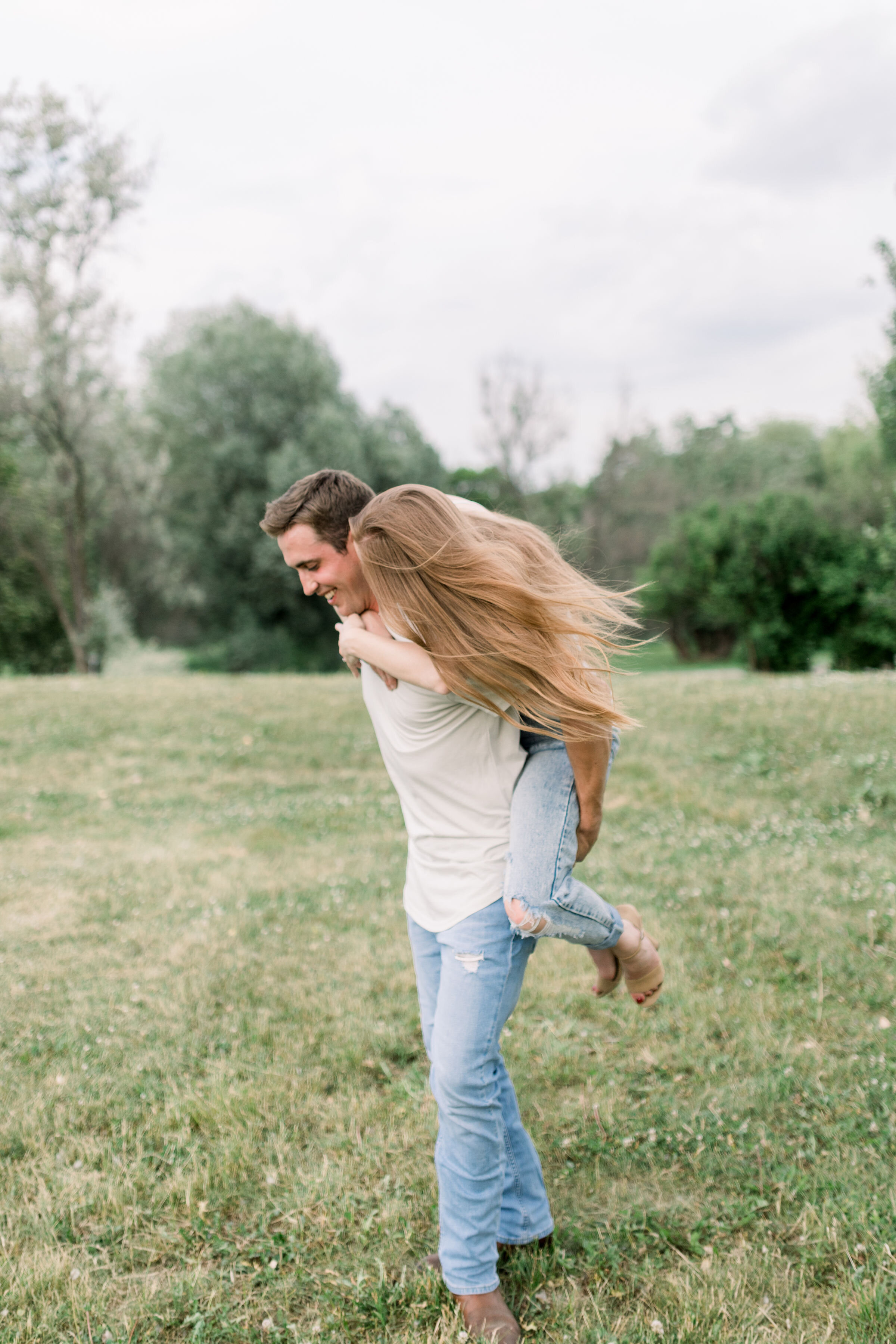  Ottawa, Ontario engagement photographer, Chelsea Mason Photography captures this woman riding her fiancé's back for a piggy back ride and kisses his cheek. woman kissing groom's cheek couple piggy back ride Ottawa engagement photographer #ChelseaMas