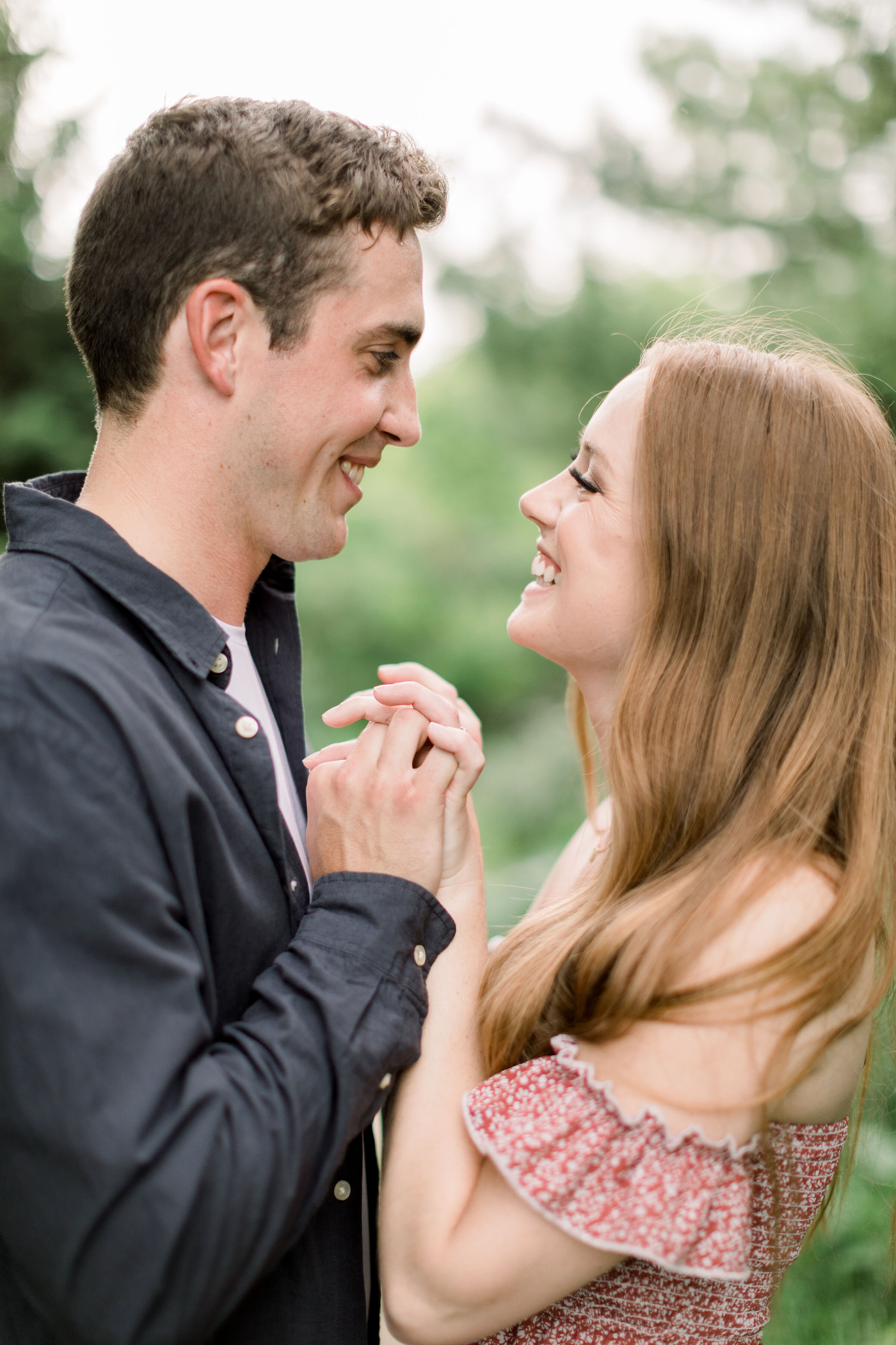  In a wooded clearing in Arboretum, Ottawa, Chelsea Mason Photography captures this engaged couple lovingly holding hands and smiling into one another's eyes. playful smiling couples photo couple holding hands in the sky arboretum engagement photogra