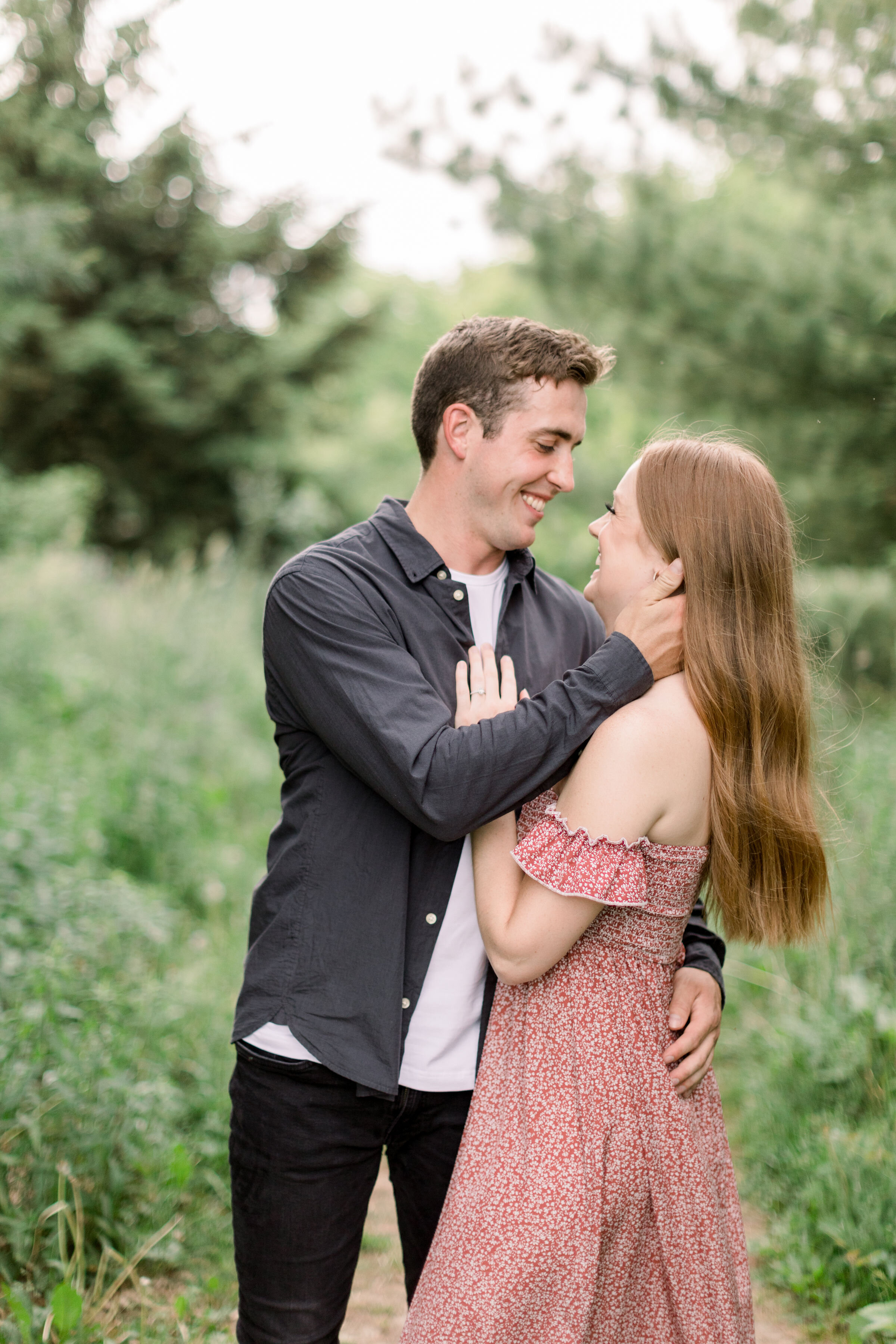  In a wooded clearing in Arboretum, Ottawa, Chelsea Mason Photography captures this engaged couple lovingly holding one another. groom cupping fiancé's face smiling couple wooded engagement session arboretum Ottawa photographer #ChelseaMasonPhotograp