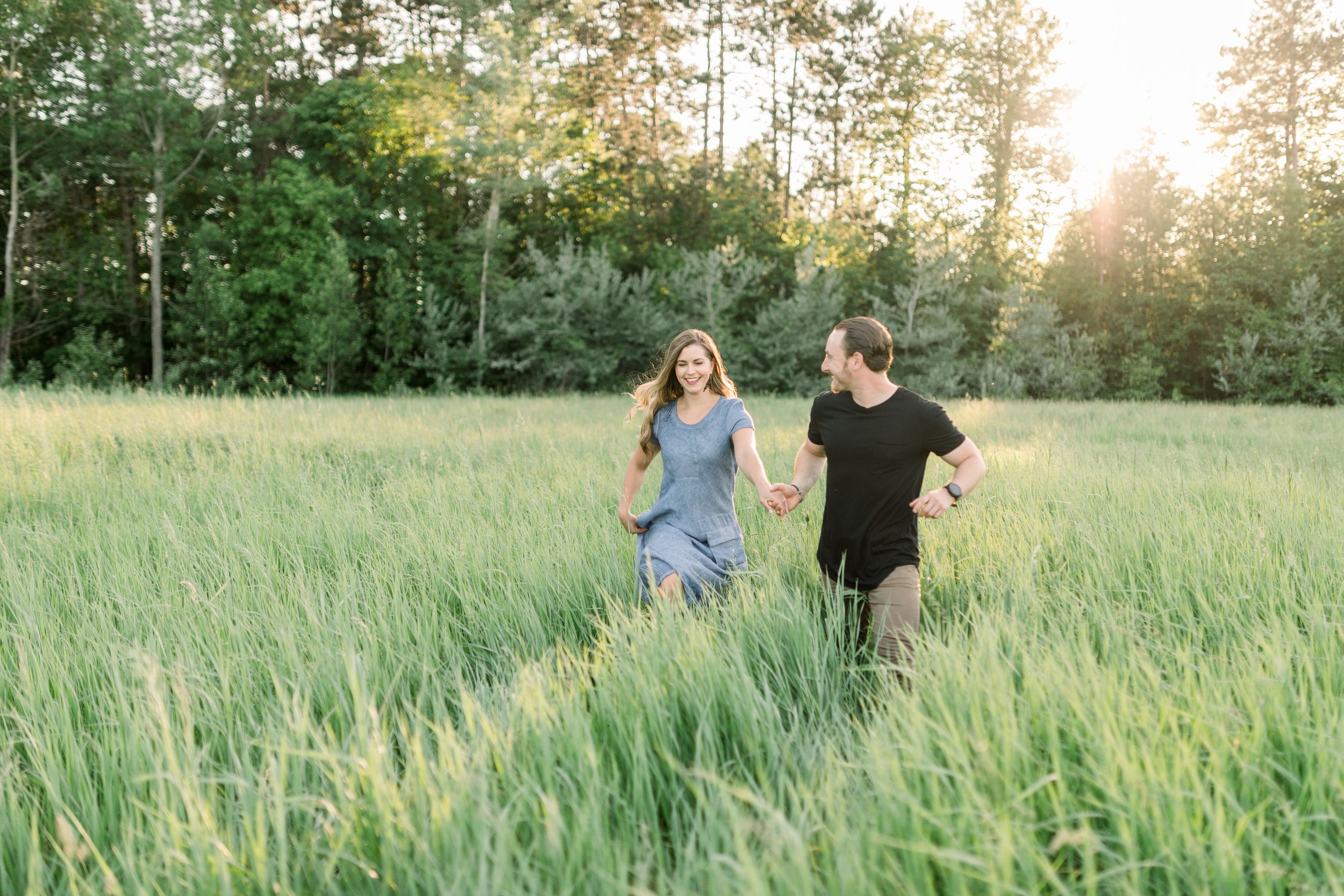  Walking in a field of grass Chelsea Mason Photography captures a wedding announcement portrait. engagements in grass field clearing #chelseamasonphotography #chelseamasonengagements #Ottawaengagments #Almonteengagementphotographer #outdoorengagments
