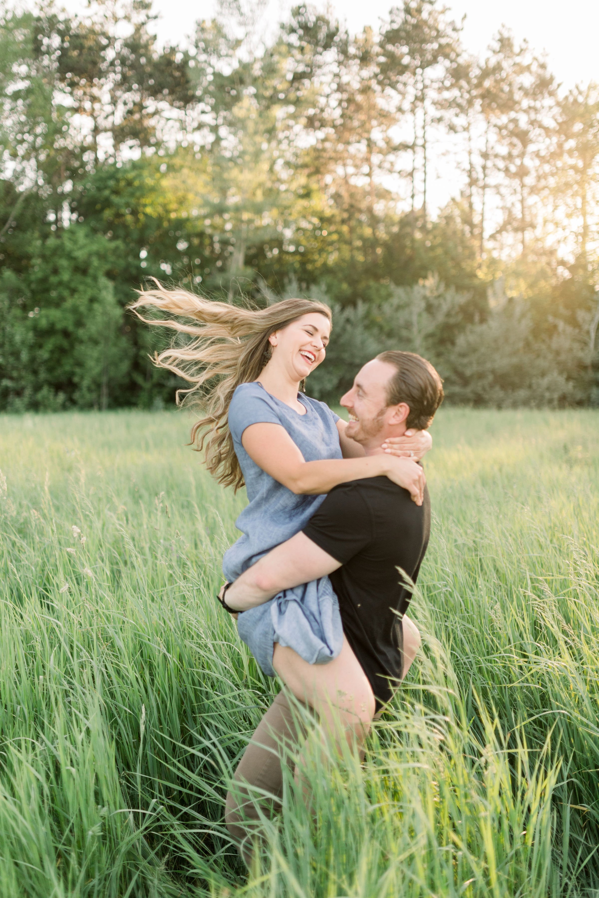  With his fiance in his arms, a man twirls her around captured by Chelsea Mason Photography in Almonte. twirling in a field #chelseamasonphotography #chelseamasonengagements #Ottawaengagments #Almonteengagementphotographer #outdoorengagments 